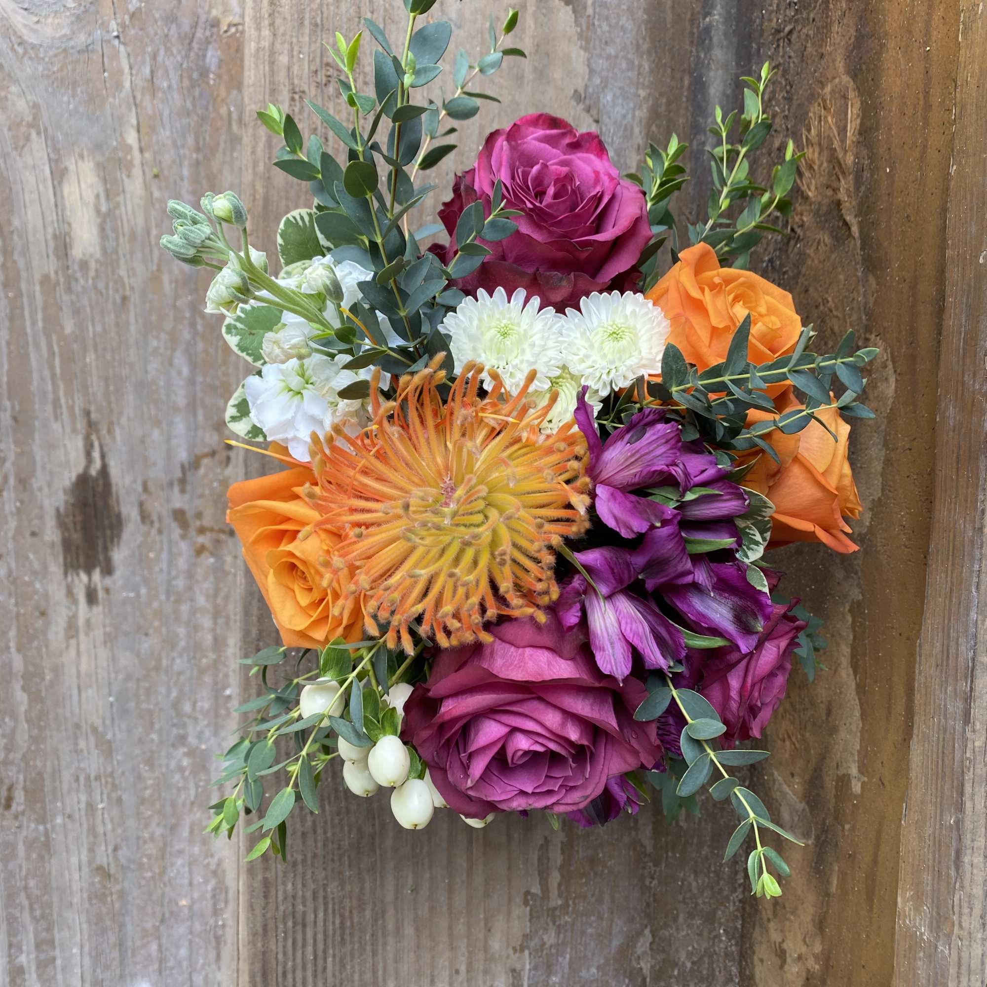 Low Arrangement in a Clear Glass Cube of jewel tone roses, pin