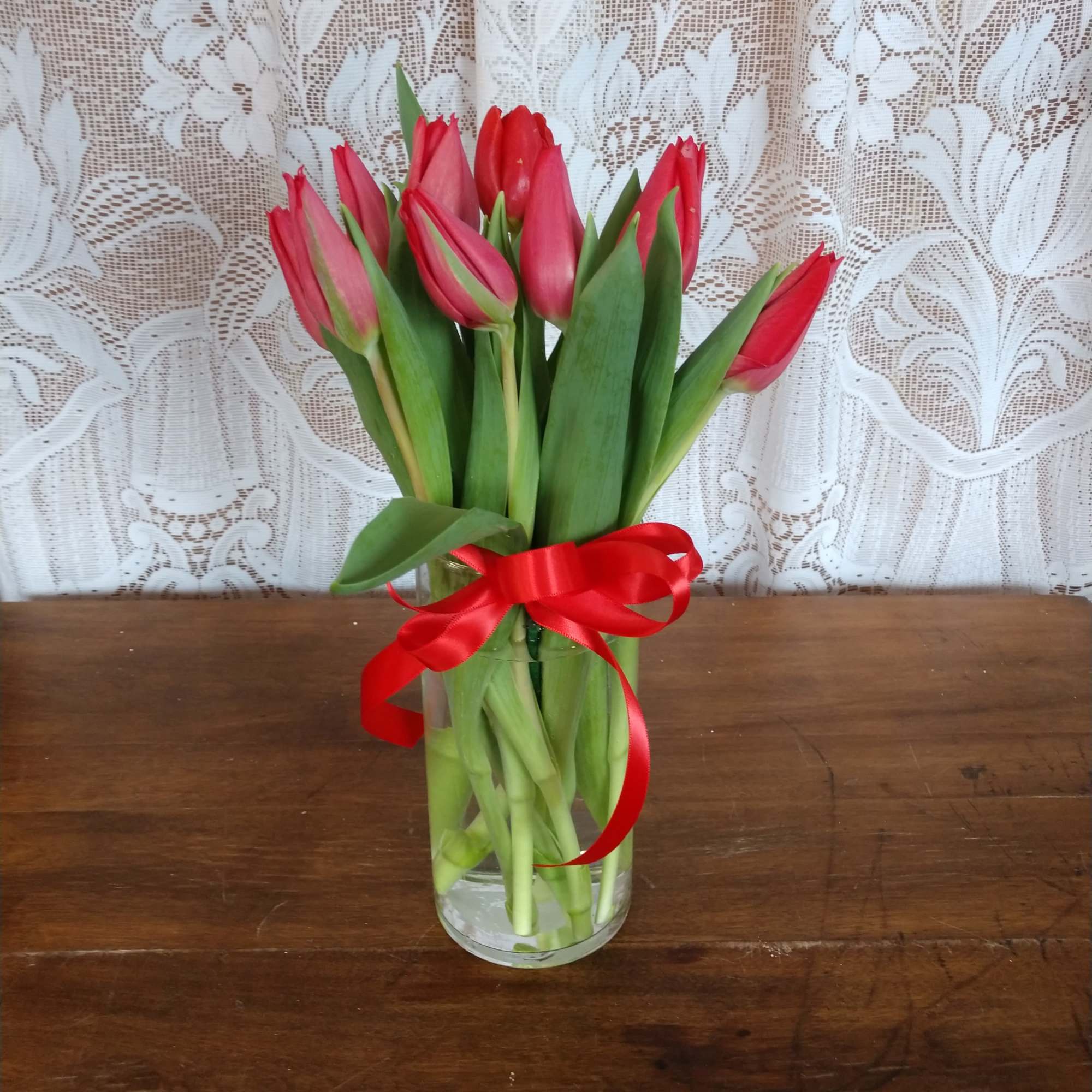 Red Tulips arranged in a glass vase.