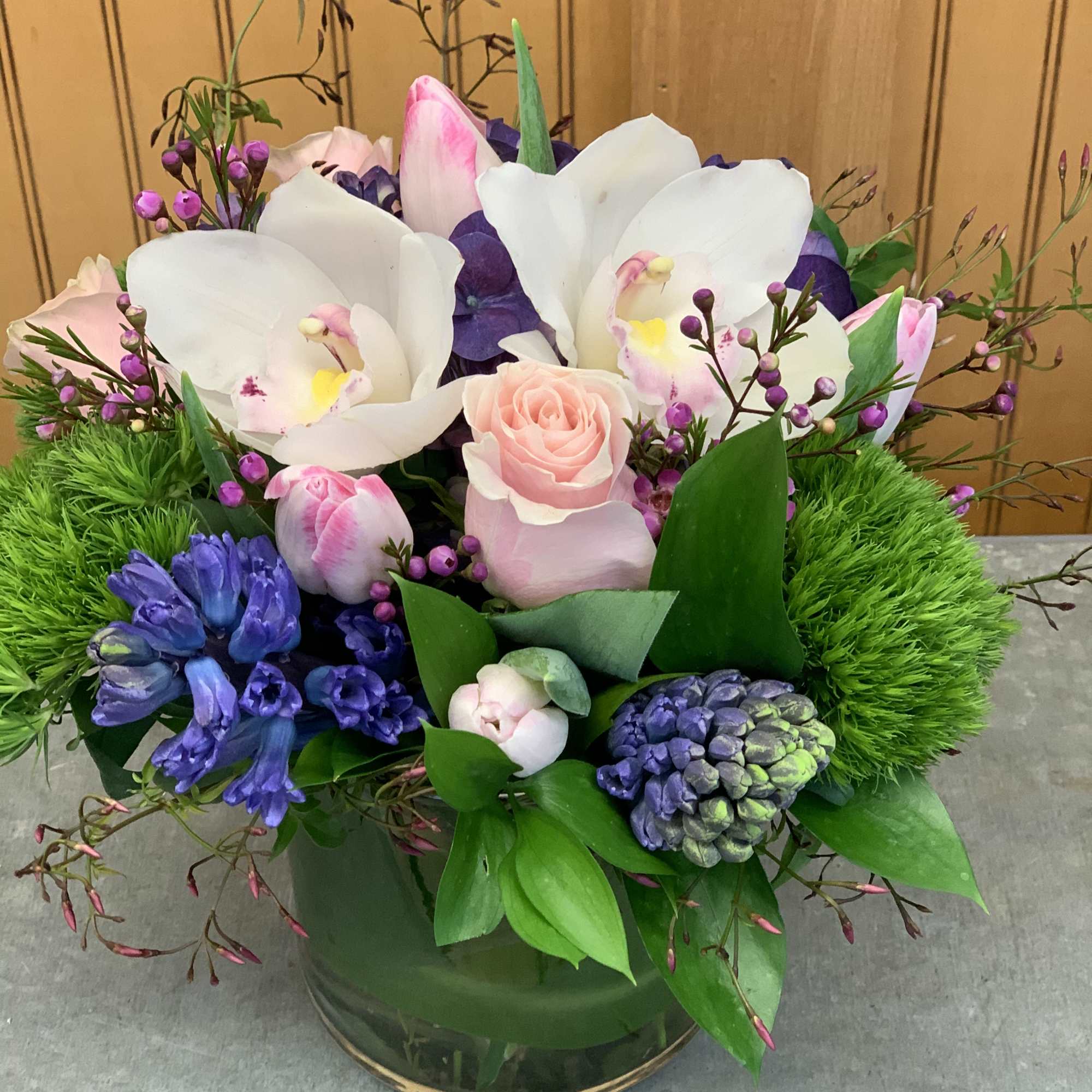 Hyacinths, tulips, roses and orchids in a cylinder vase. 
