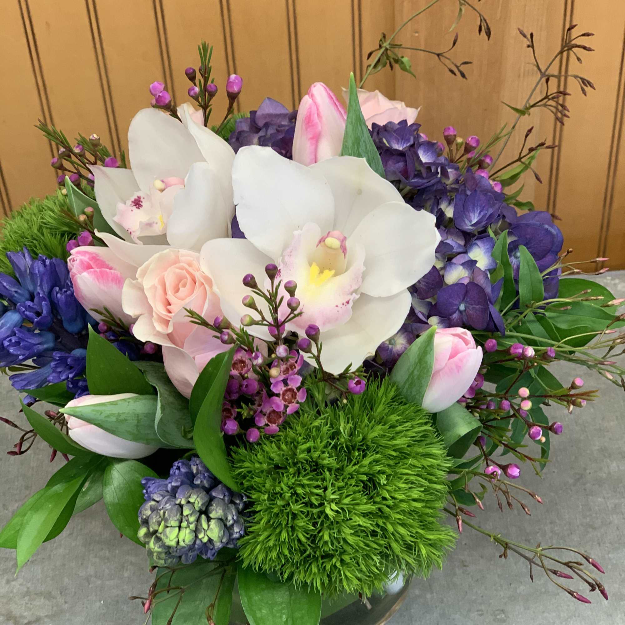 Hyacinths, tulips, roses and orchids in a cylinder vase. 