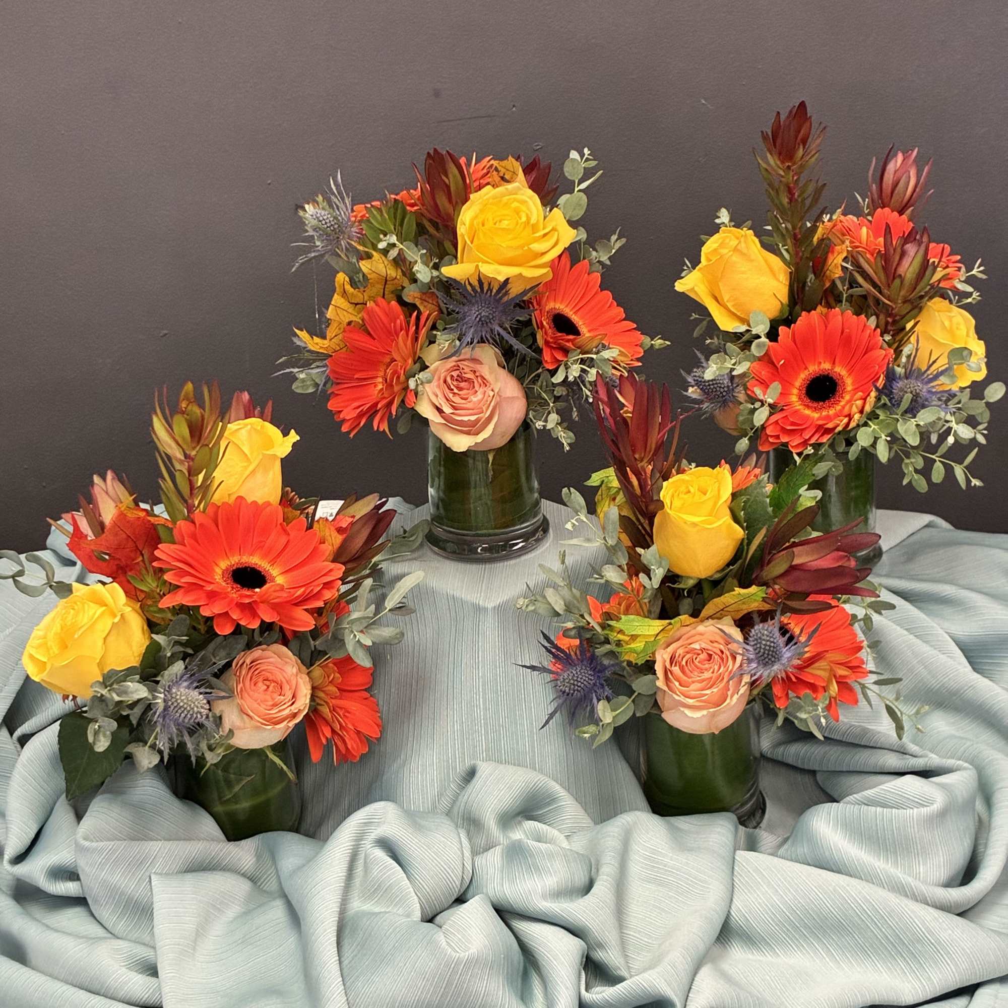 petite arrangements glow with sunset-inspired warmth and texture. Each green glass vase