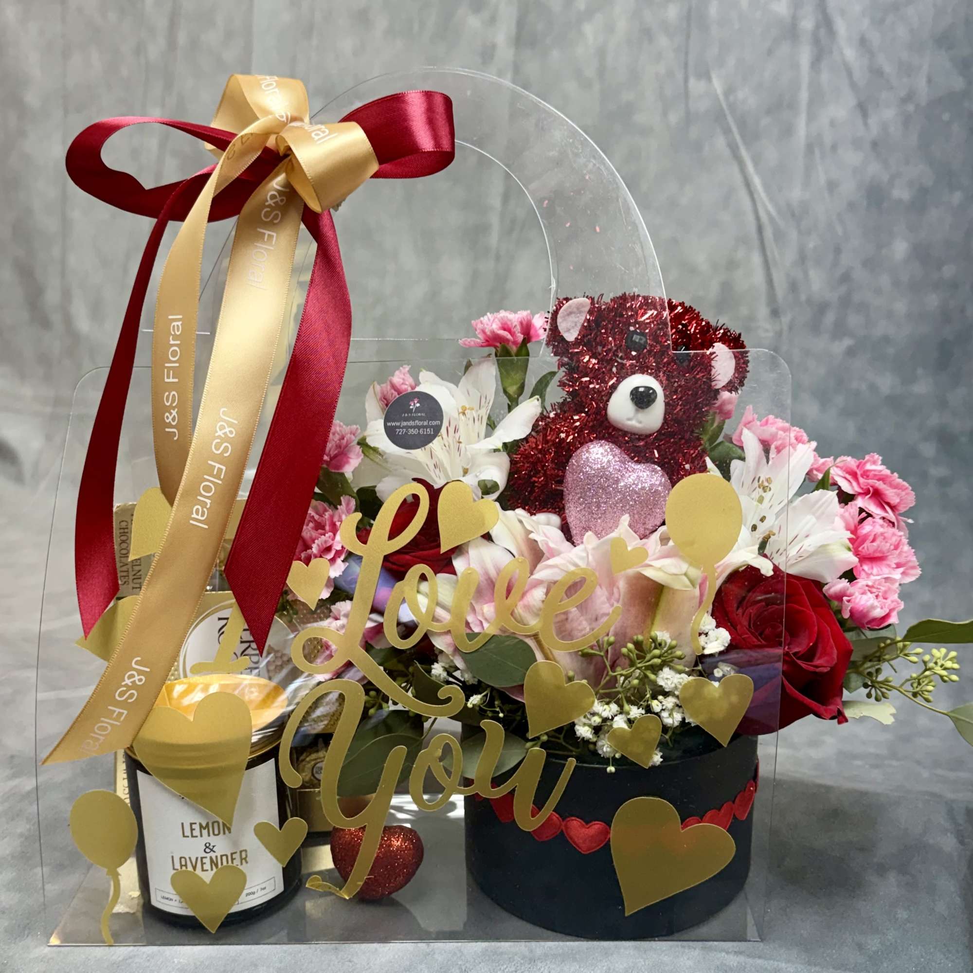 A stunning floral box accompanied by a fragrant candle and gourmet chocolates