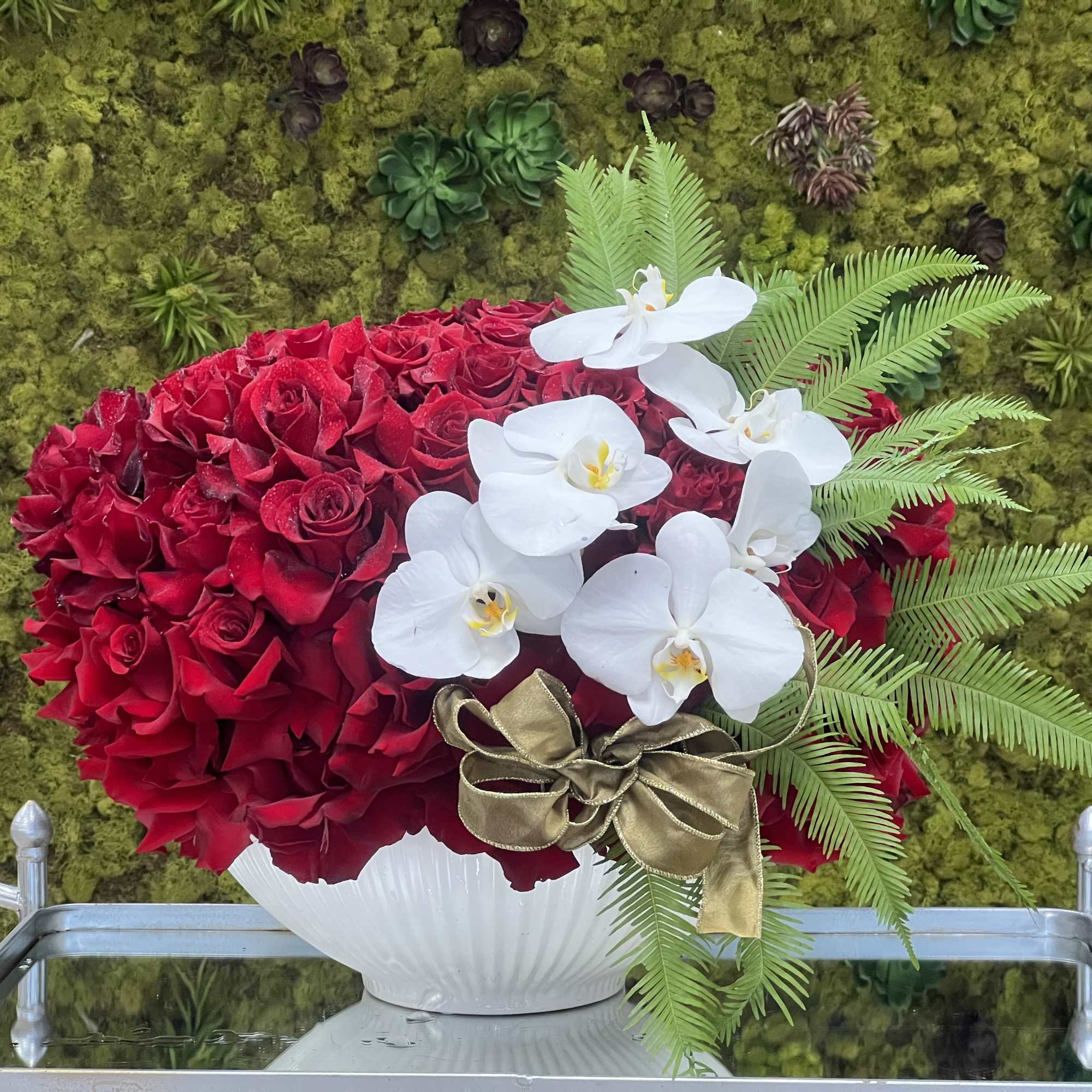 Gorgeous red Roses are accented with white Phalaenopsis Orchids in a low