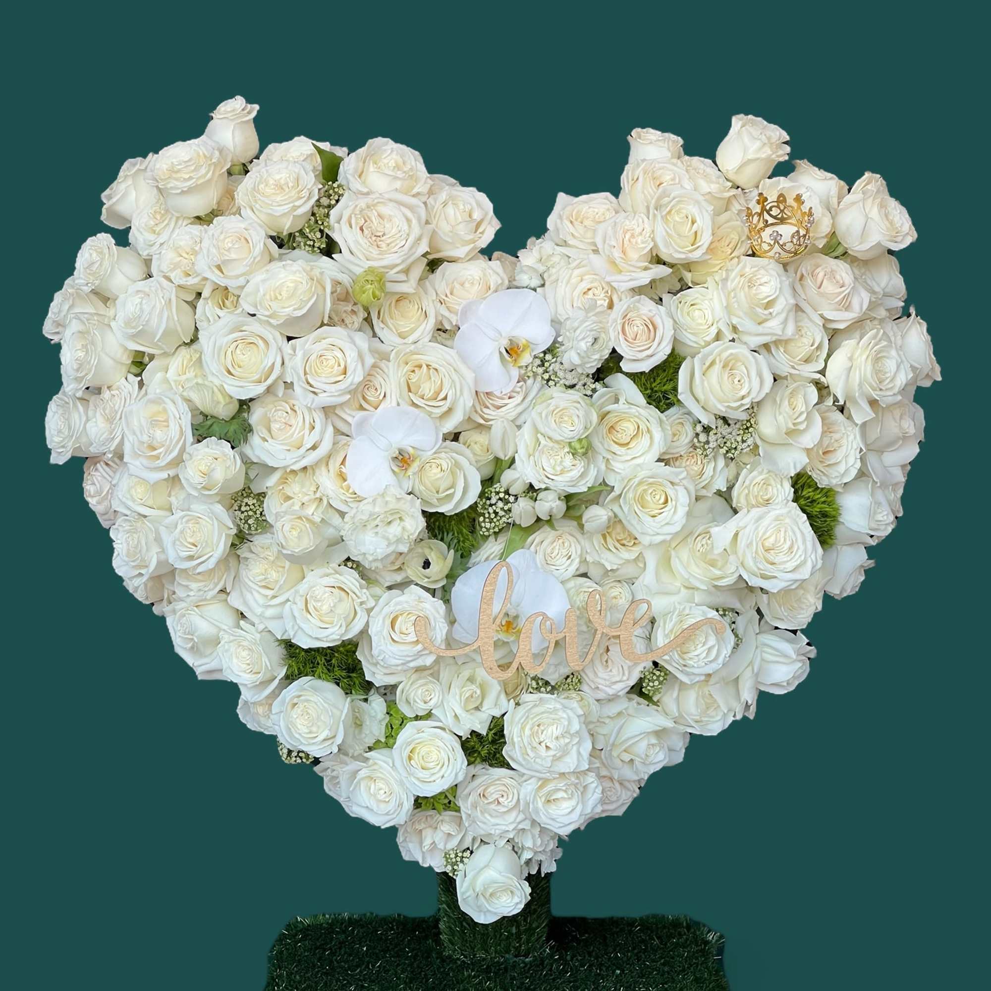 A heart-shaped standing arrangement, filled with white Roses, finished with white Phalaenopsis