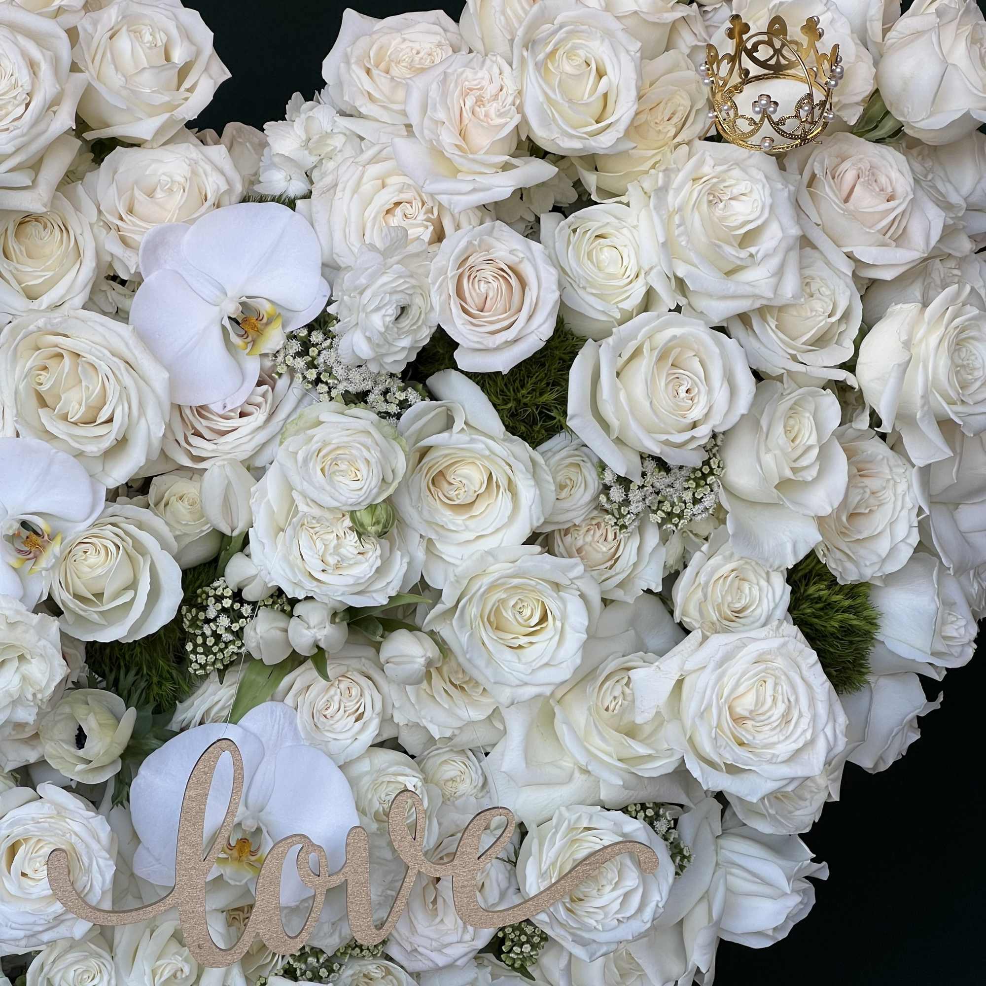 A heart-shaped standing arrangement, filled with white Roses, finished with white Phalaenopsis