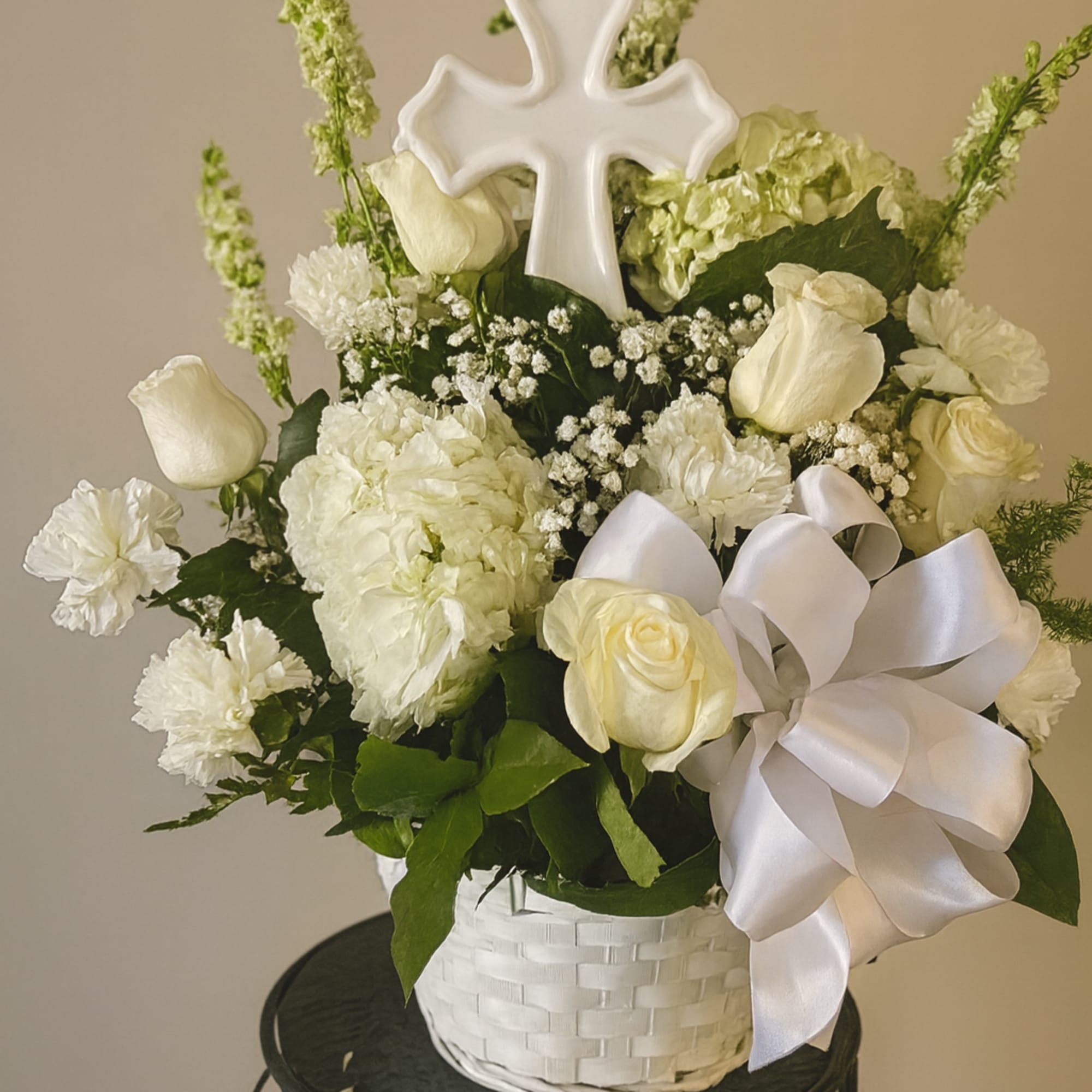 fresh white flowers in basket with large cross 