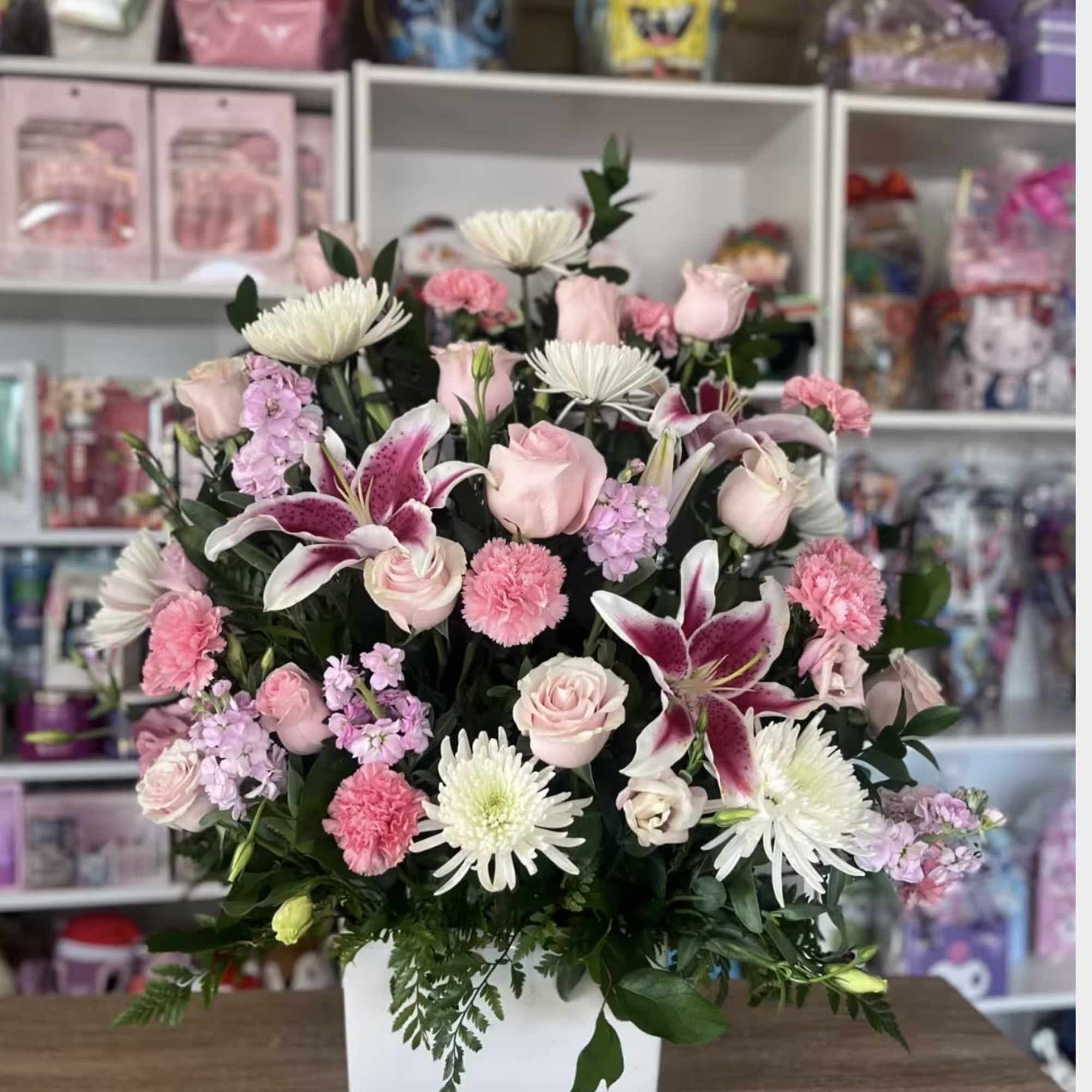 This pink and white funeral in square white vase 
 includes Banner