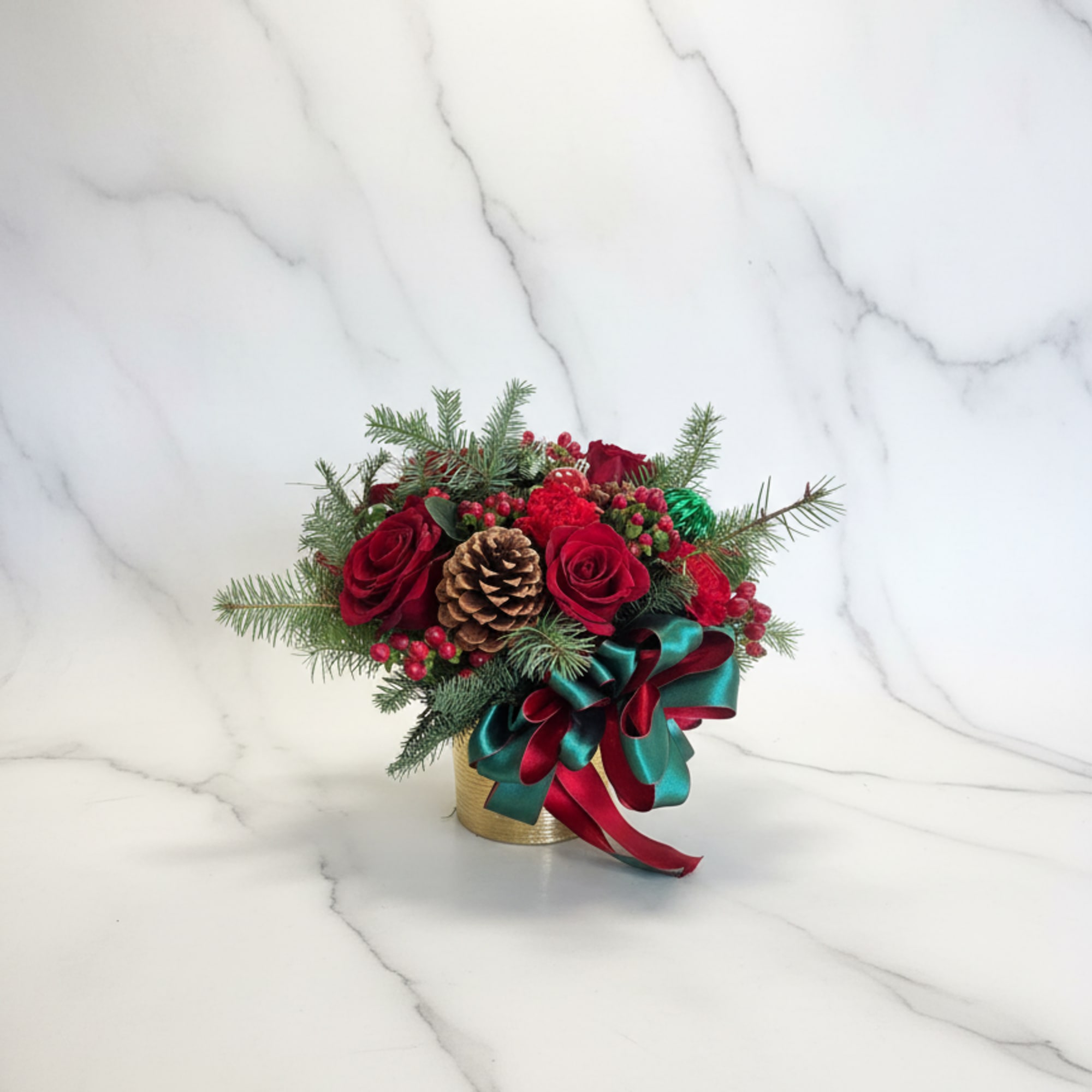 A warm Christmas mix of red roses, berries, pine cones, and evergreens