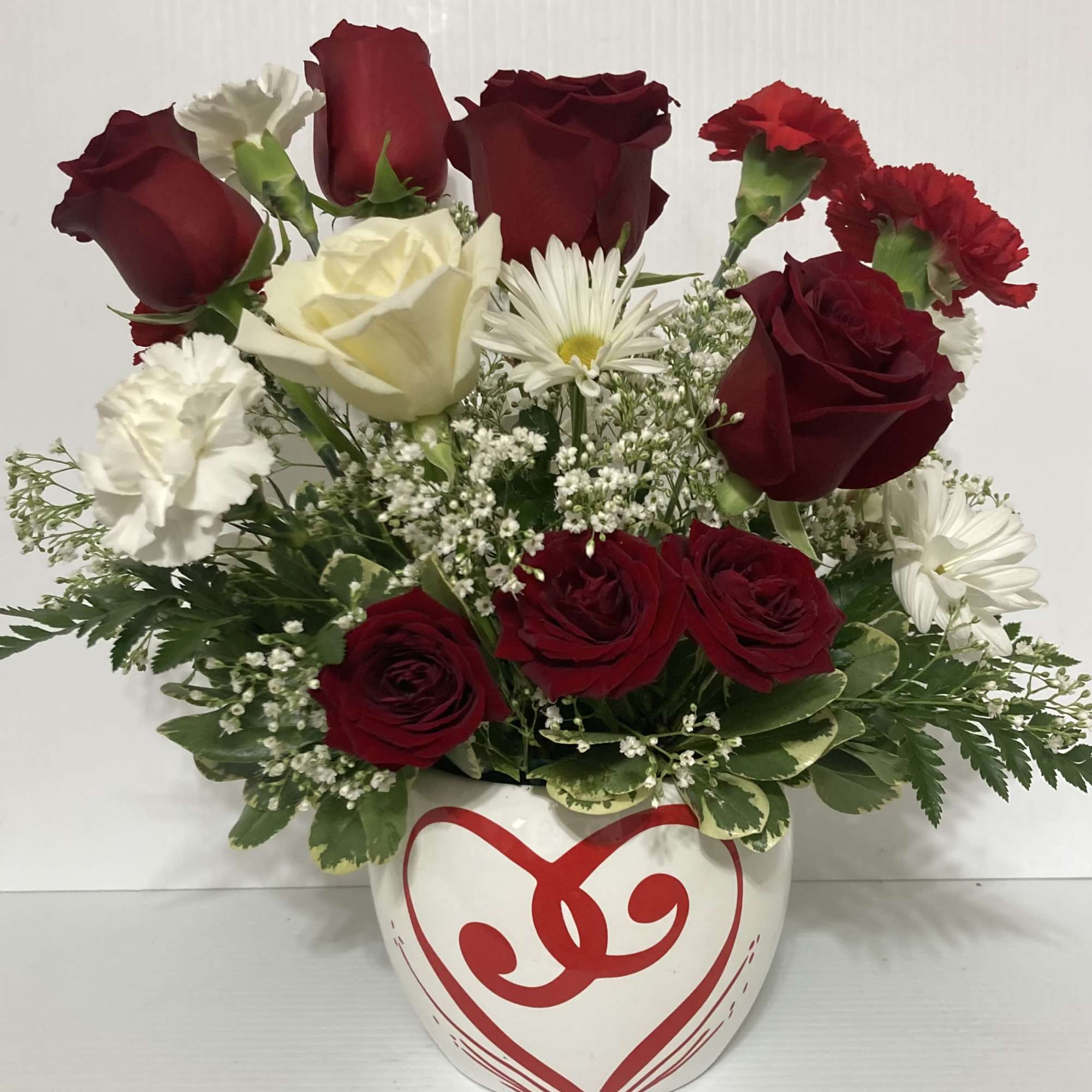 Beautiful arrangement with Roses, Carnations, greens in a decorative heart vase