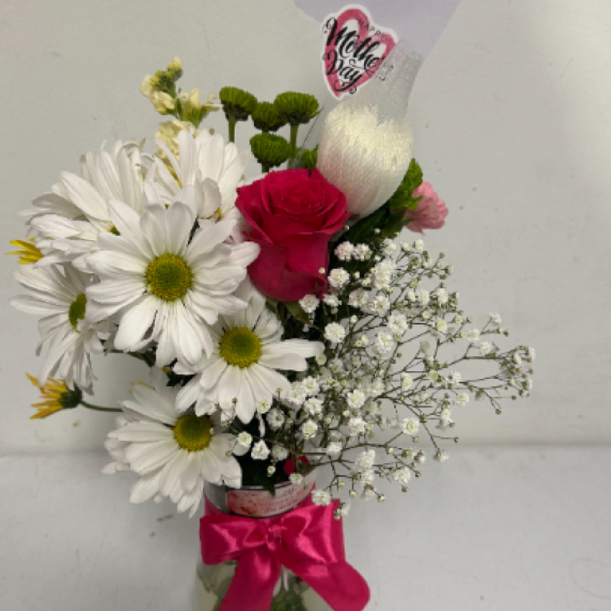 Floral arrangement with different flowers in a glass container and ribbon, a