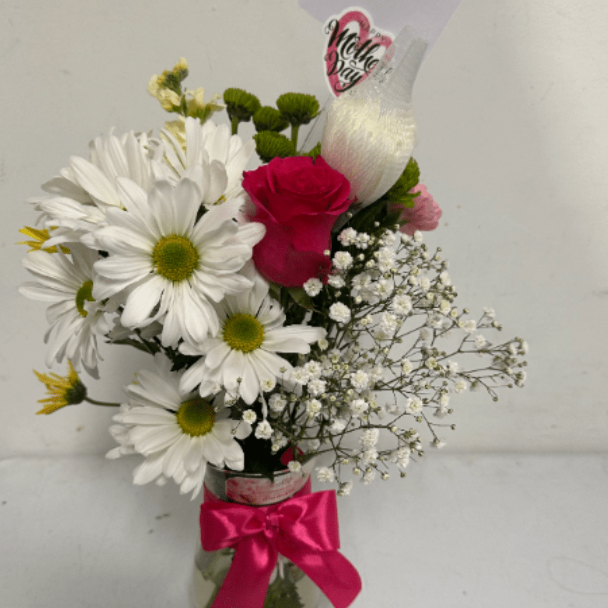 Floral arrangement with different flowers in a glass container and ribbon, a