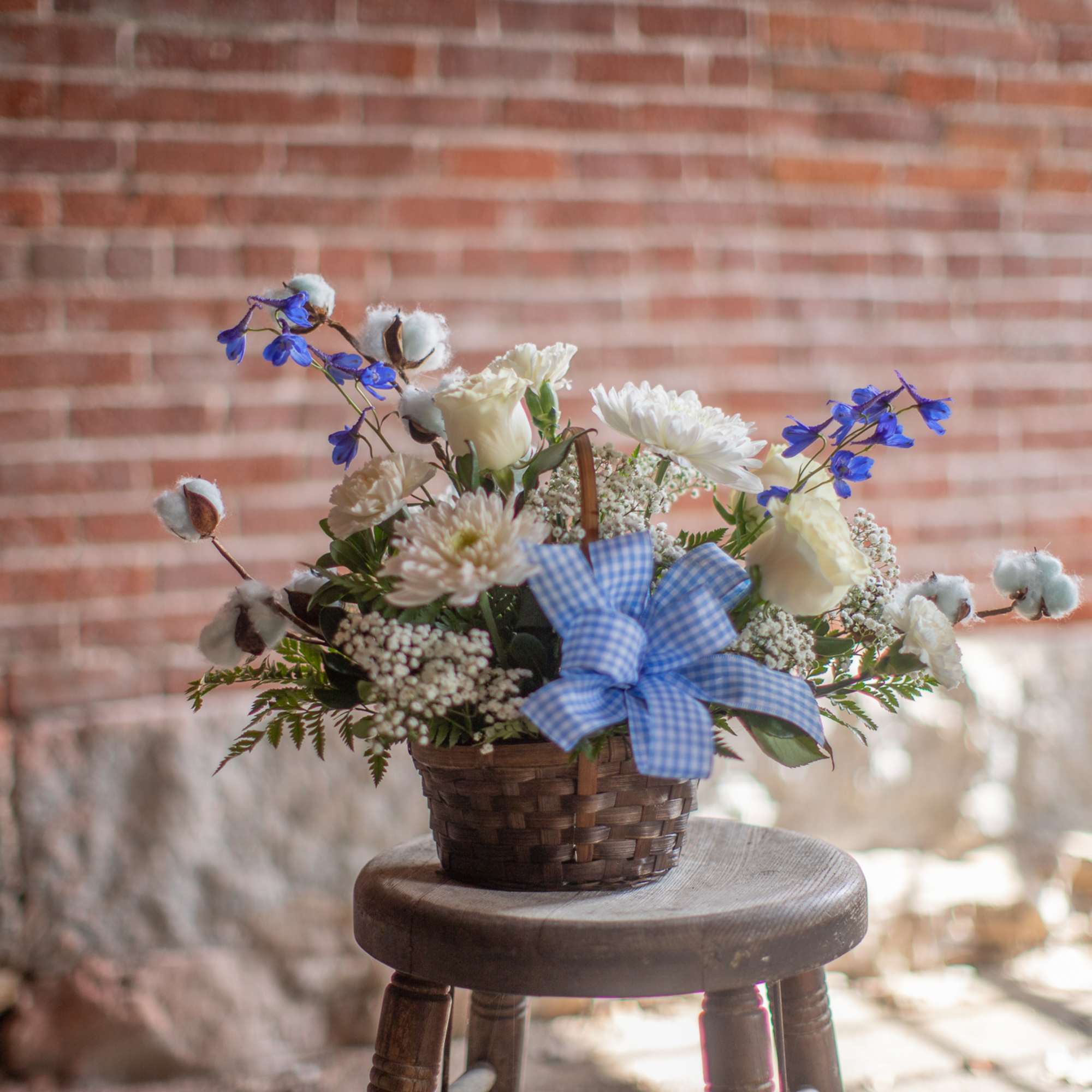 Delicate puffs of pink or blue cotton branches surround a fresh floral