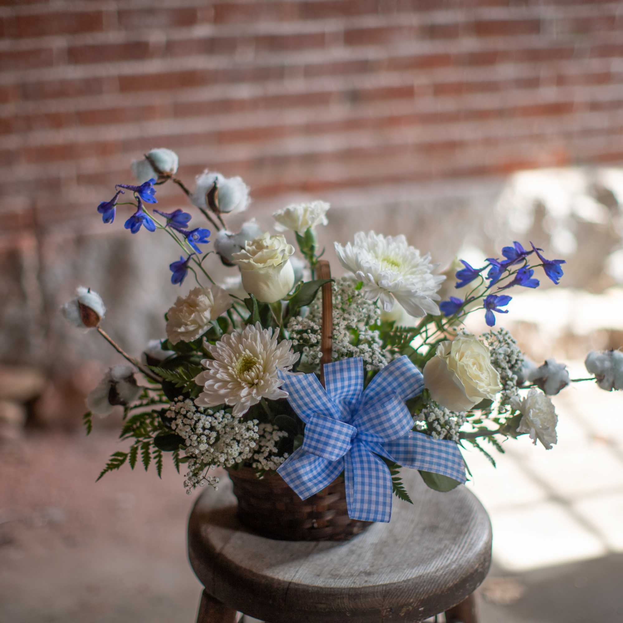 Delicate puffs of pink or blue cotton branches surround a fresh floral