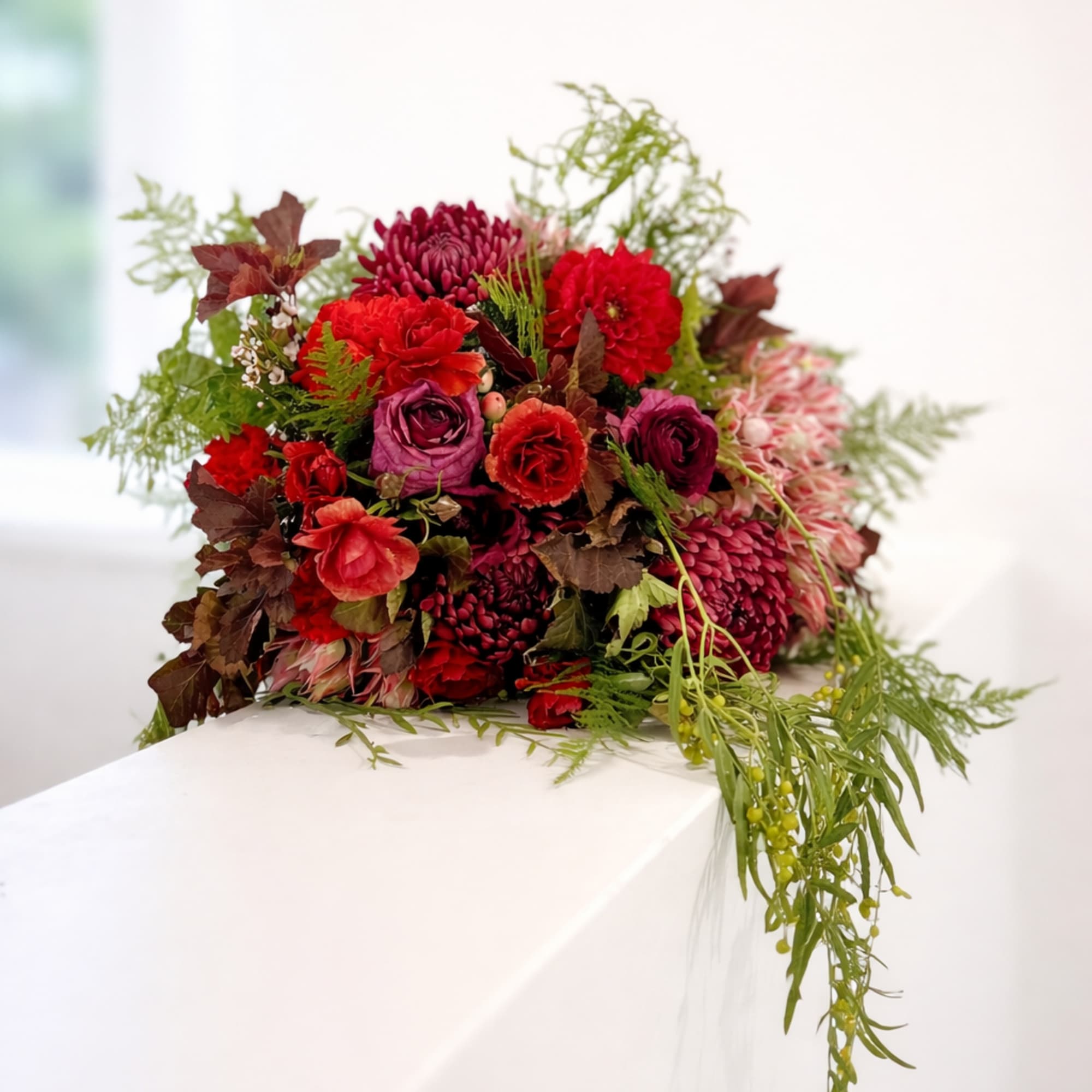 This bouquet is a dramatic and romantic gathering of jewel-toned blooms with