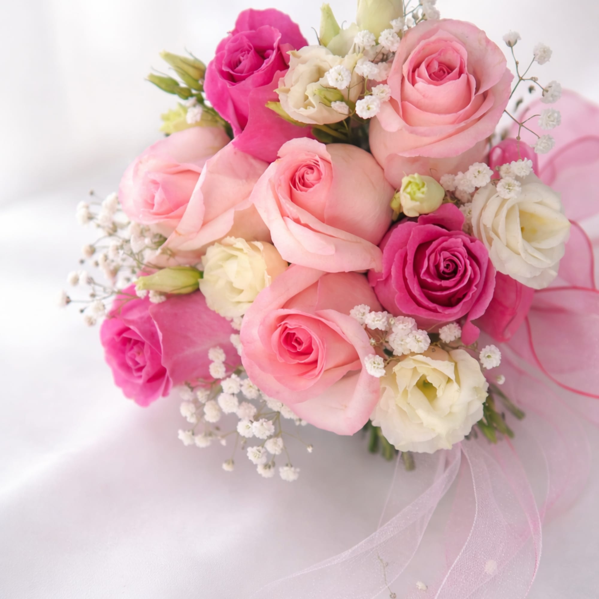 Soft pink roses, white lisianthus, and baby&rsquo;s breath arranged in a clear