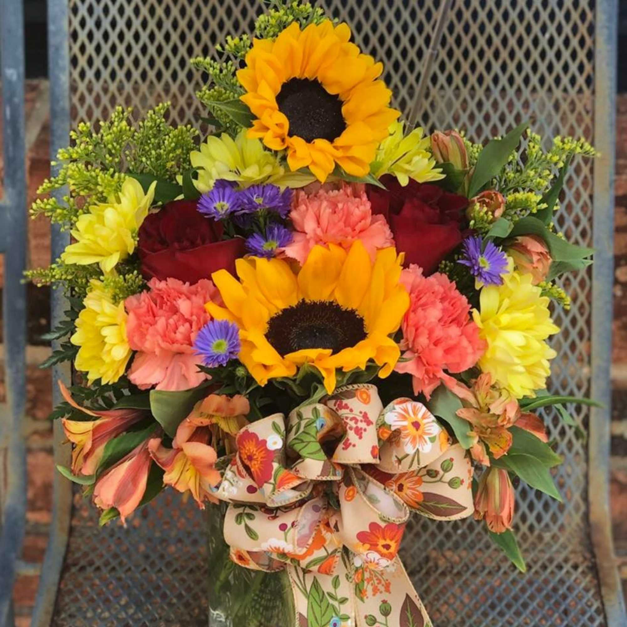 A mason jar filled with some of summer best, sunflowers, daisies, solidego