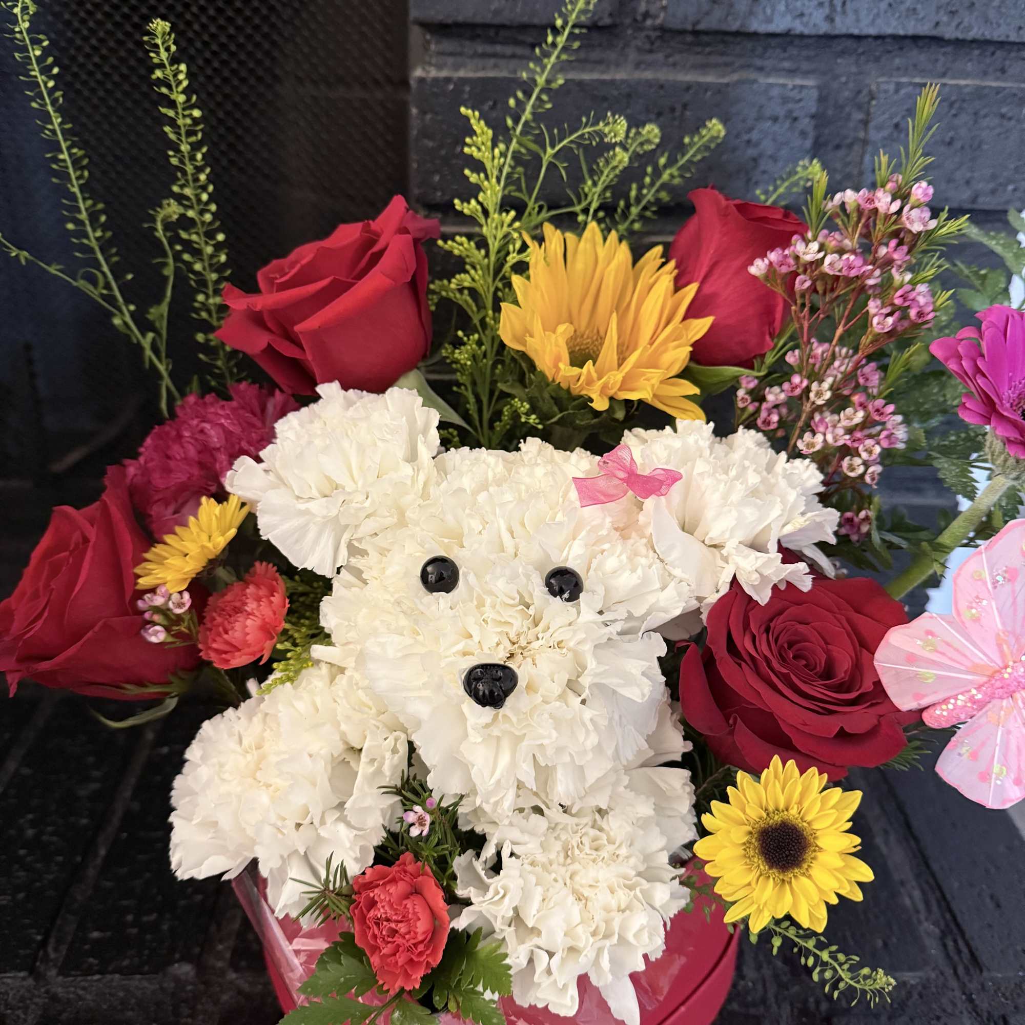This charming arrangement features an adorable puppy handcrafted from fresh white carnations