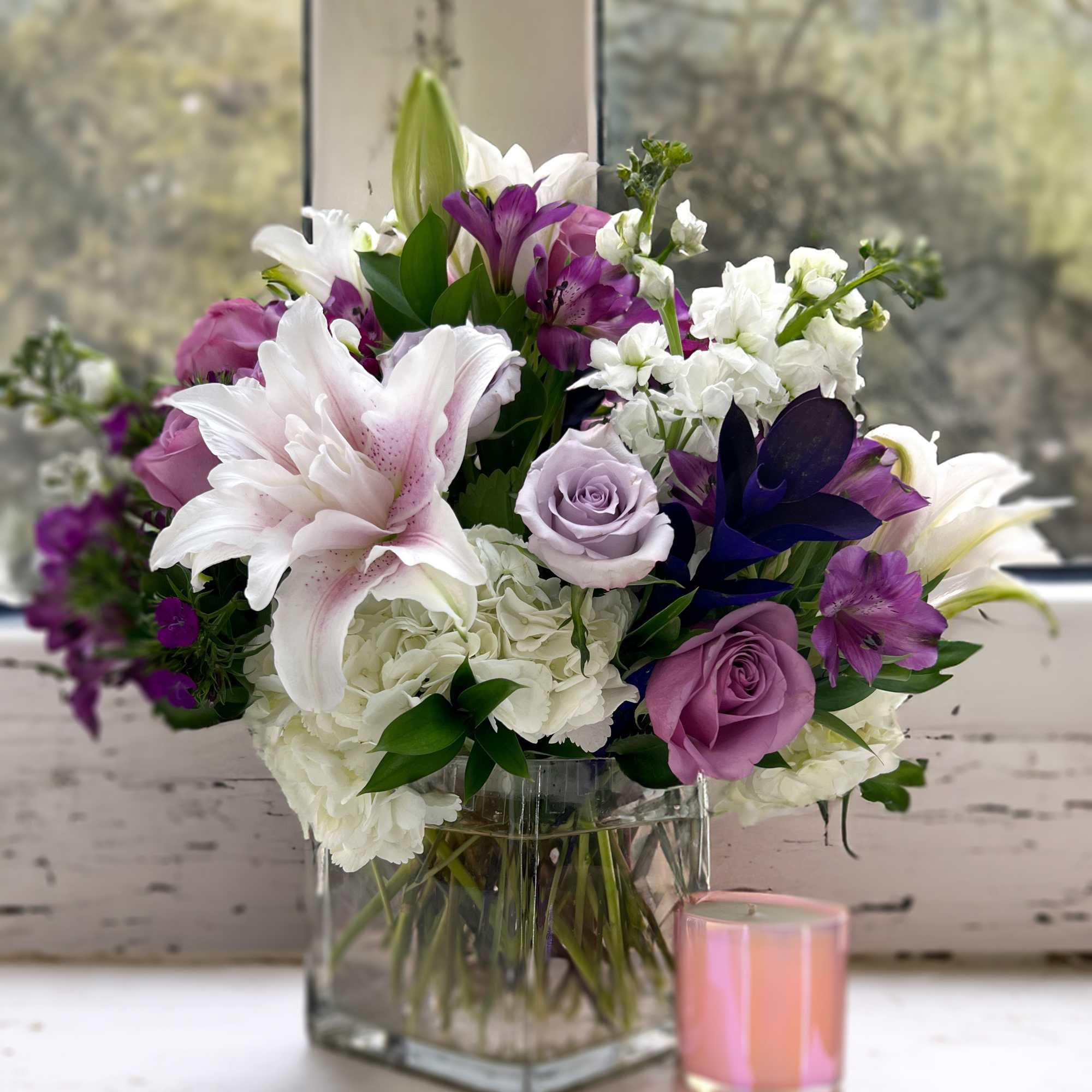 Enjoy getting lost in this arrangement of lavender roses, deep purple ruscus
