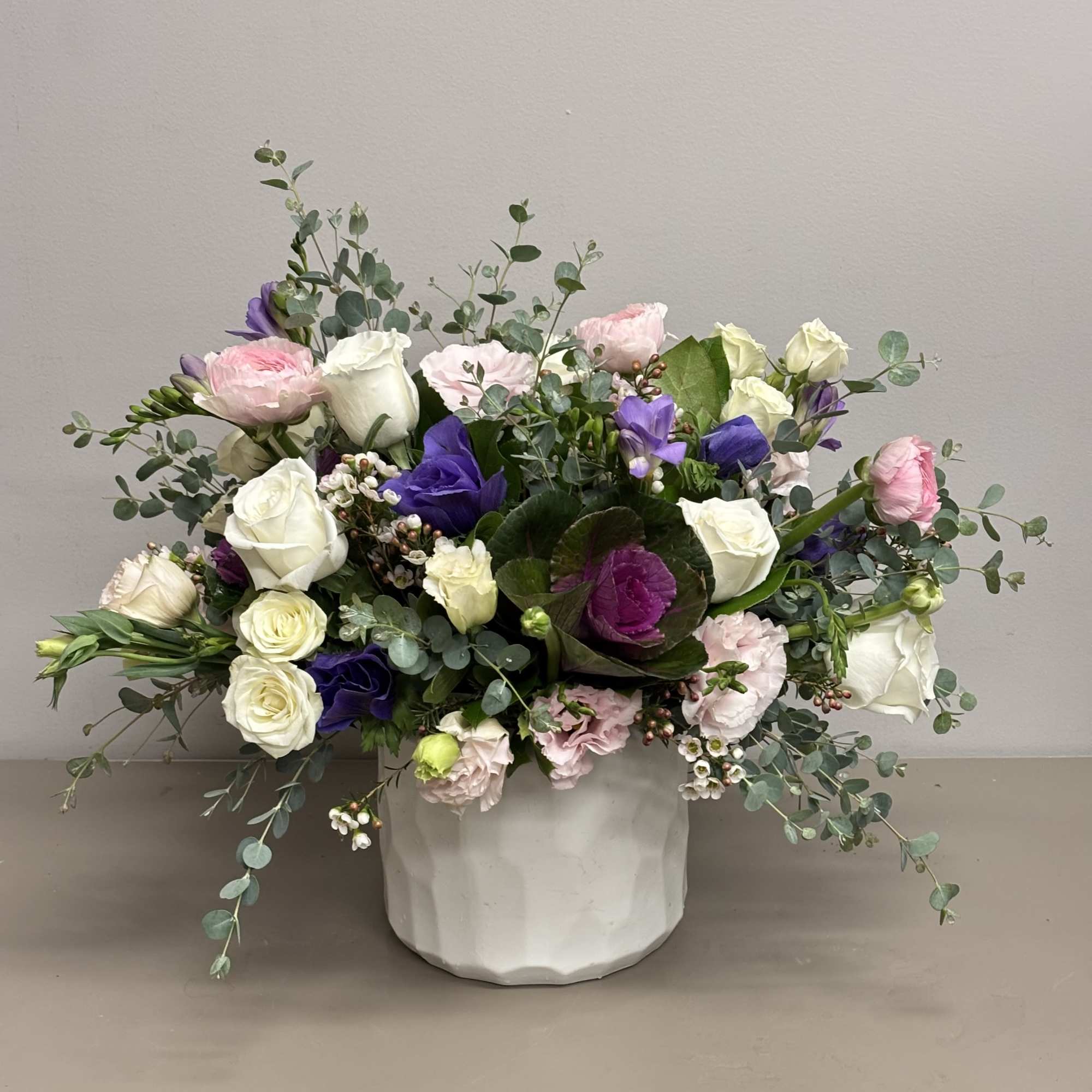 A garden style arrangement beautifully designed with Roses, Ranunculus, Lisianthus, Kale and