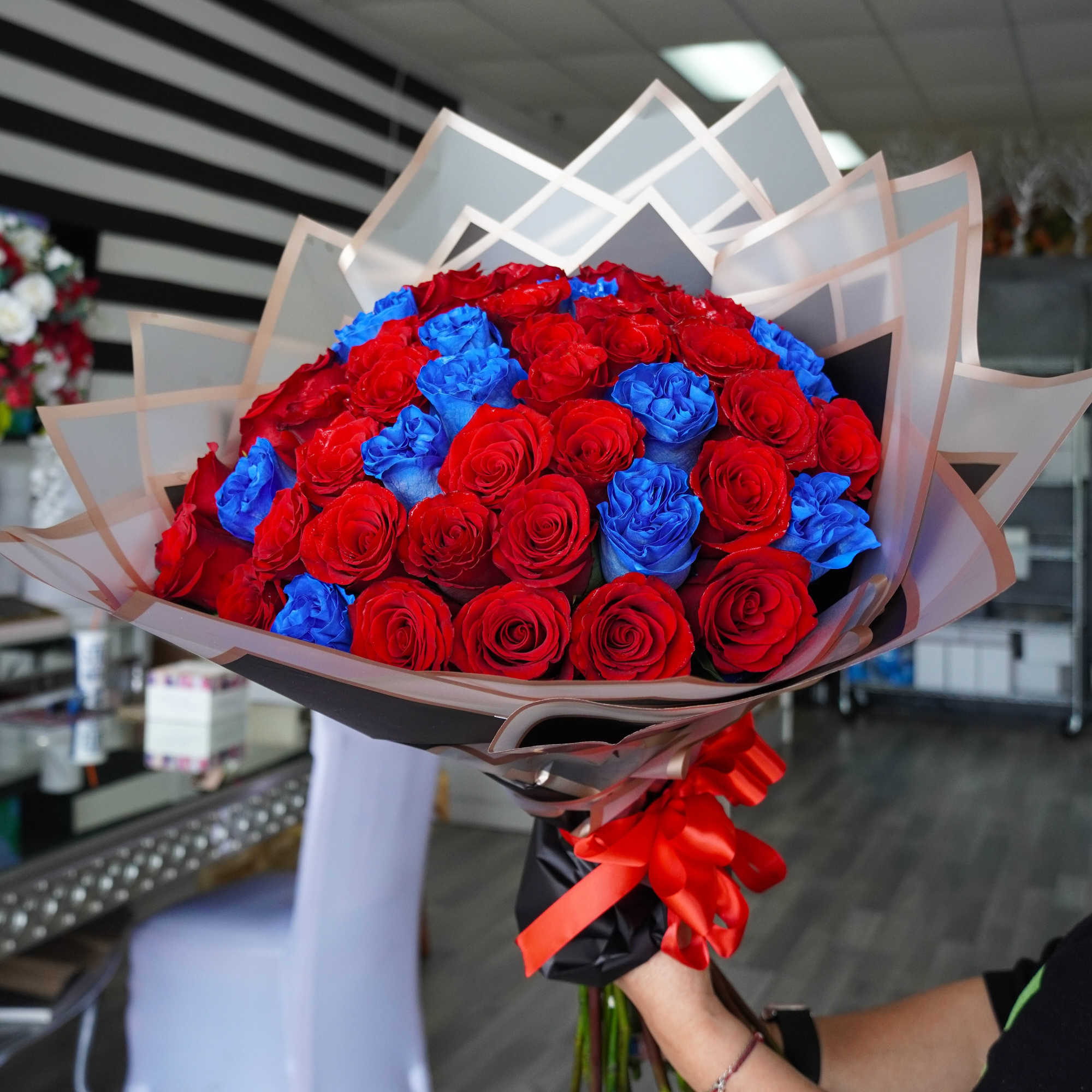 A bold bouquet of red and blue long stem roses, beautifully wrapped