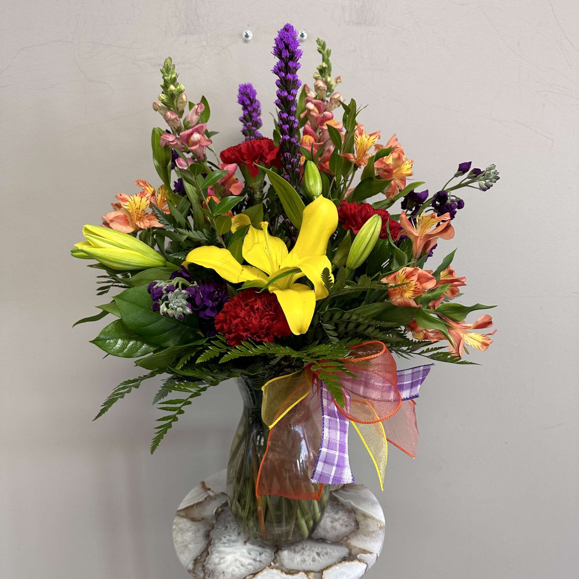 A mix of orange snapdragons, purple larkspur, red carnations, yellow asiatic lilies