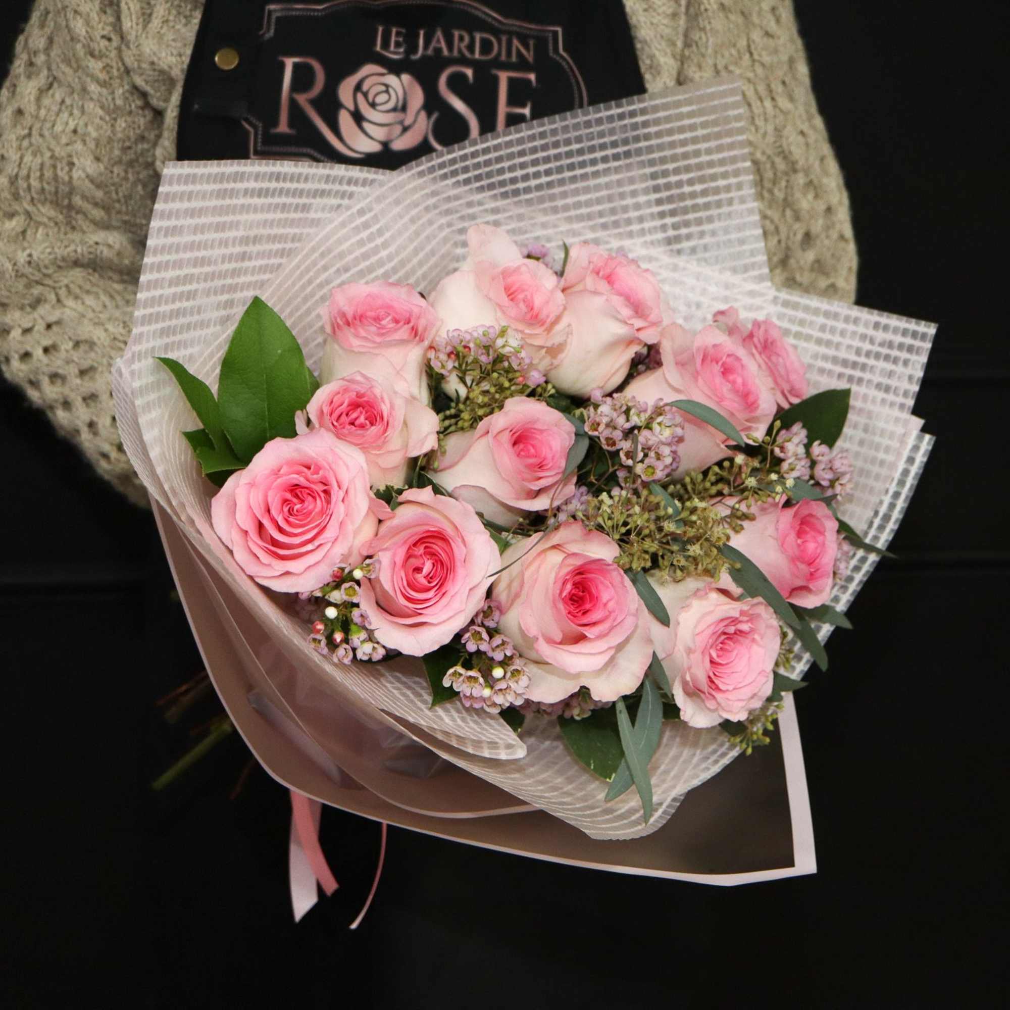 A classic one dozen pink roses with pink/white wax flowers.