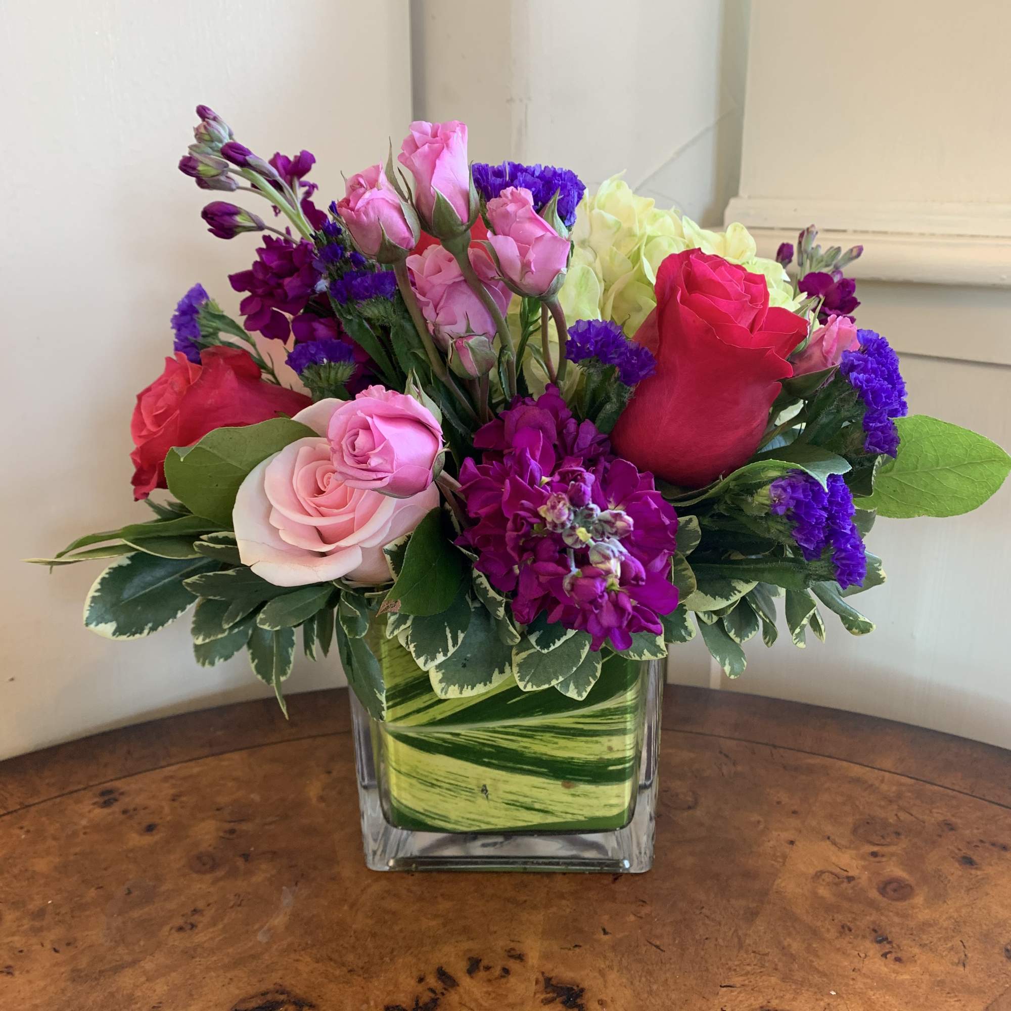 This arrangement includes hot pink roses, pink roses, green hydrangea, lavender spray