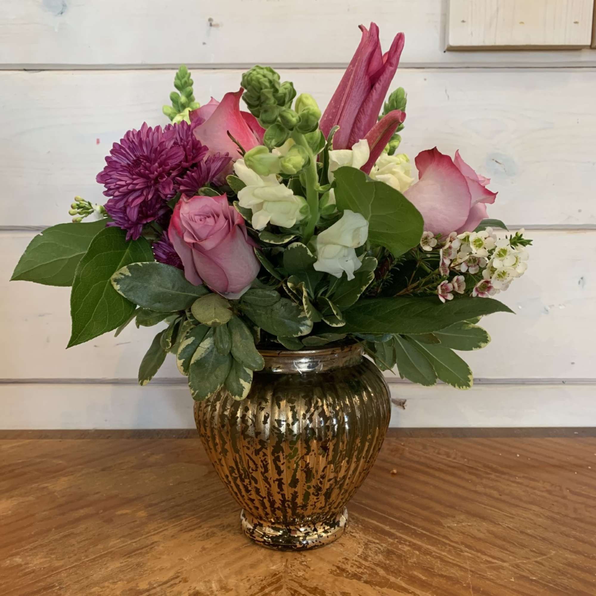 Lavender roses, chrysanthemums, white snaps and pink lily bloom arranged in mercury