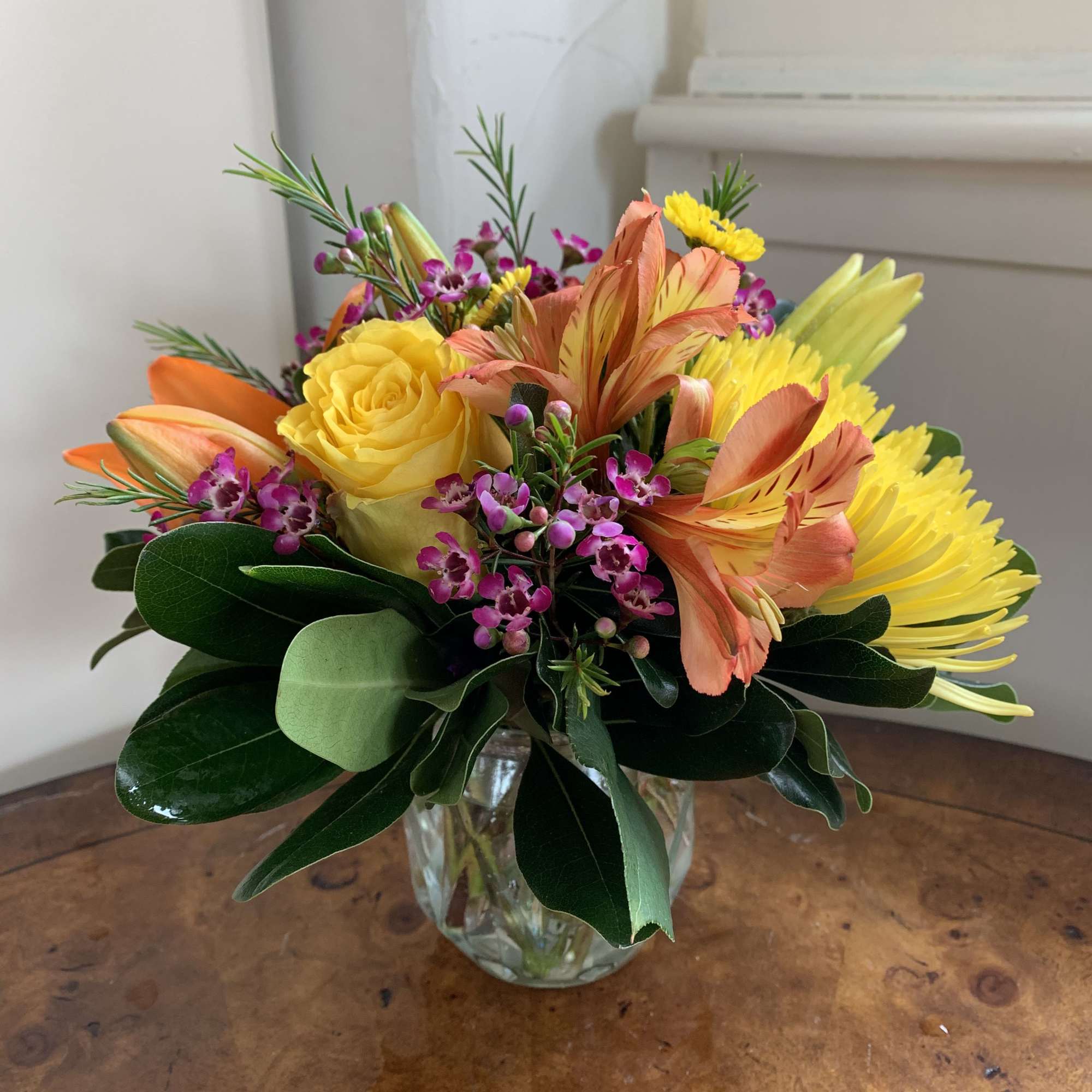 Yellow roses, orange lily, yellow spider chrysanthemum, and orange alstroemeria, arranged in