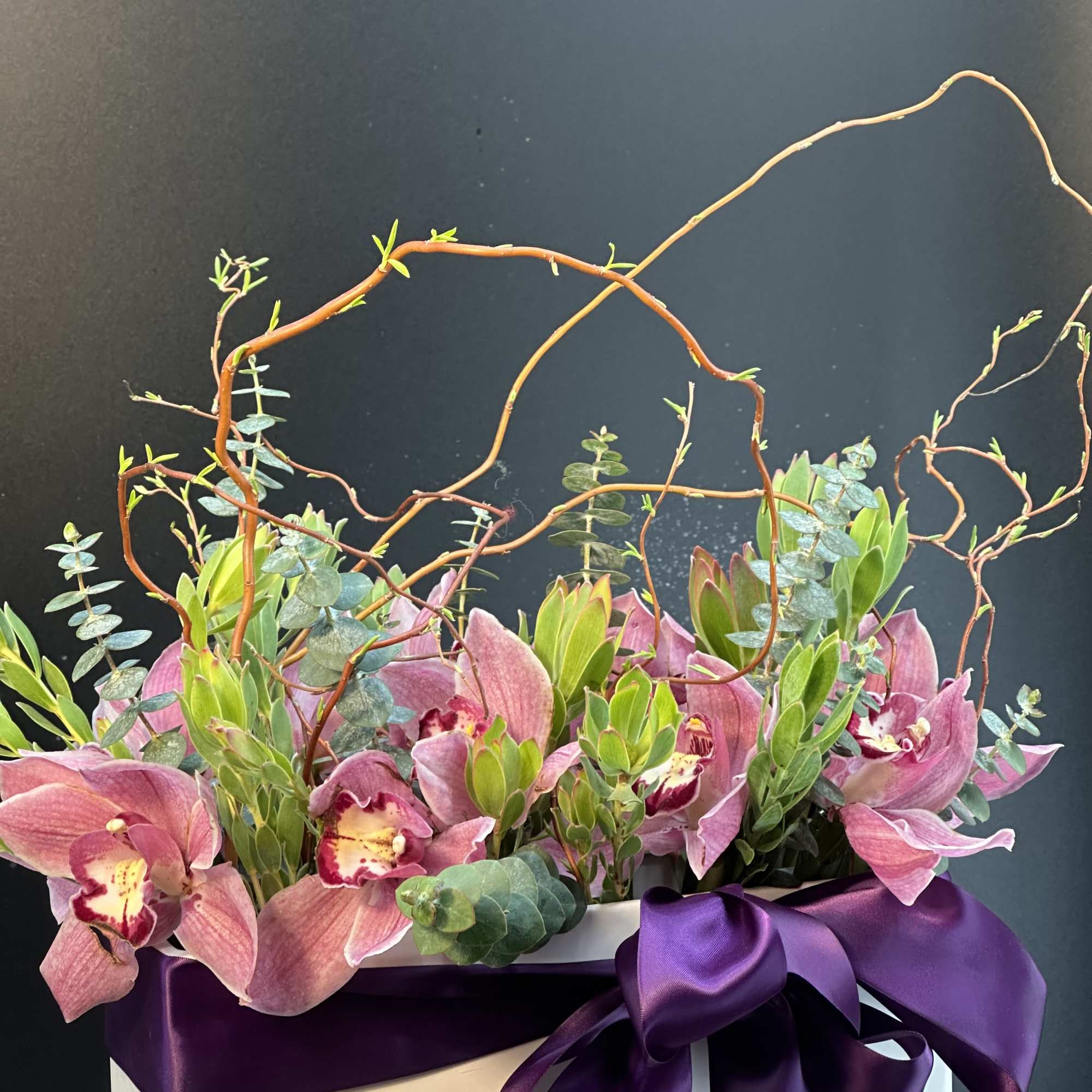 A striking composition of lush orchids ,sculptural greenery ,and artistic branches elegantly