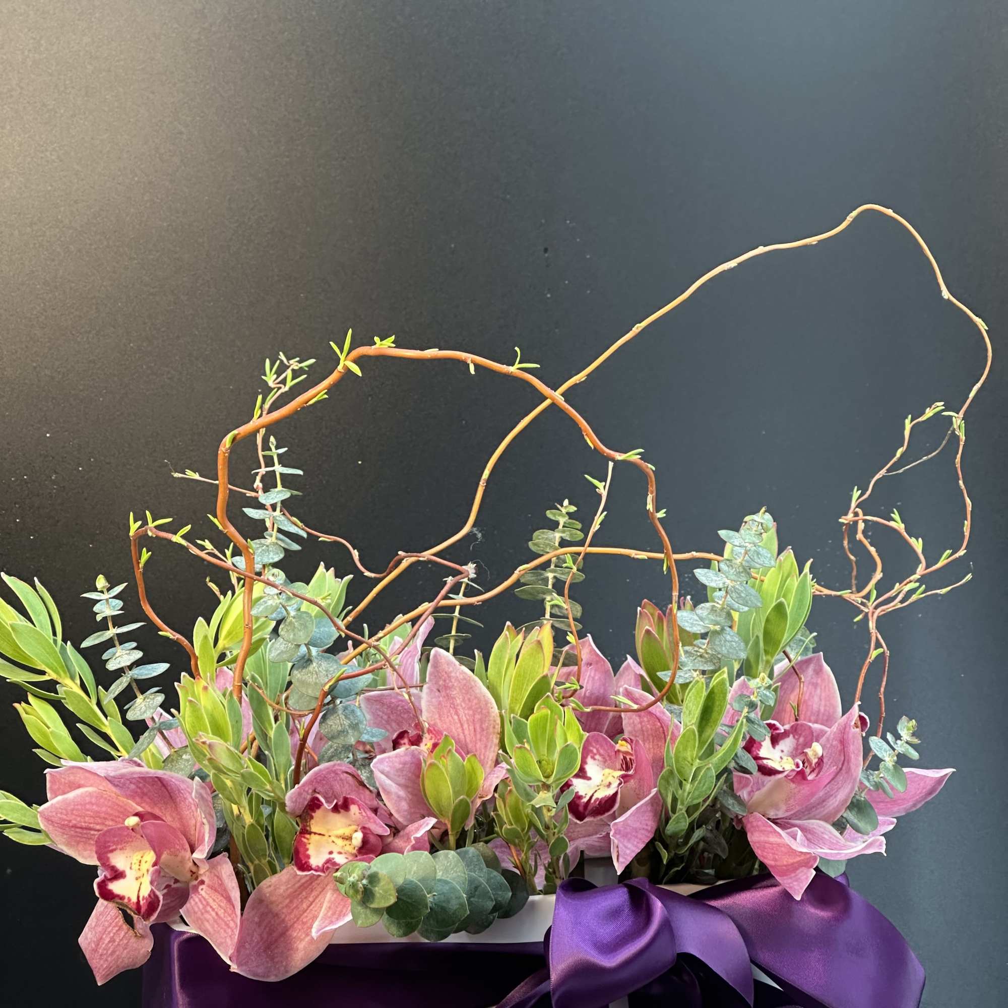 A striking composition of lush orchids ,sculptural greenery ,and artistic branches elegantly
