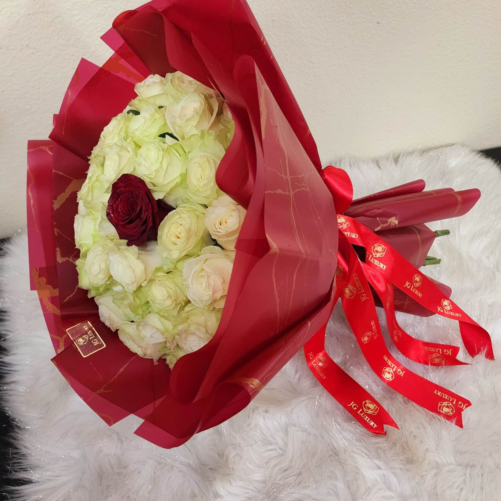 Soft creamy yellow roses, crowned by a solitary red rose which rises