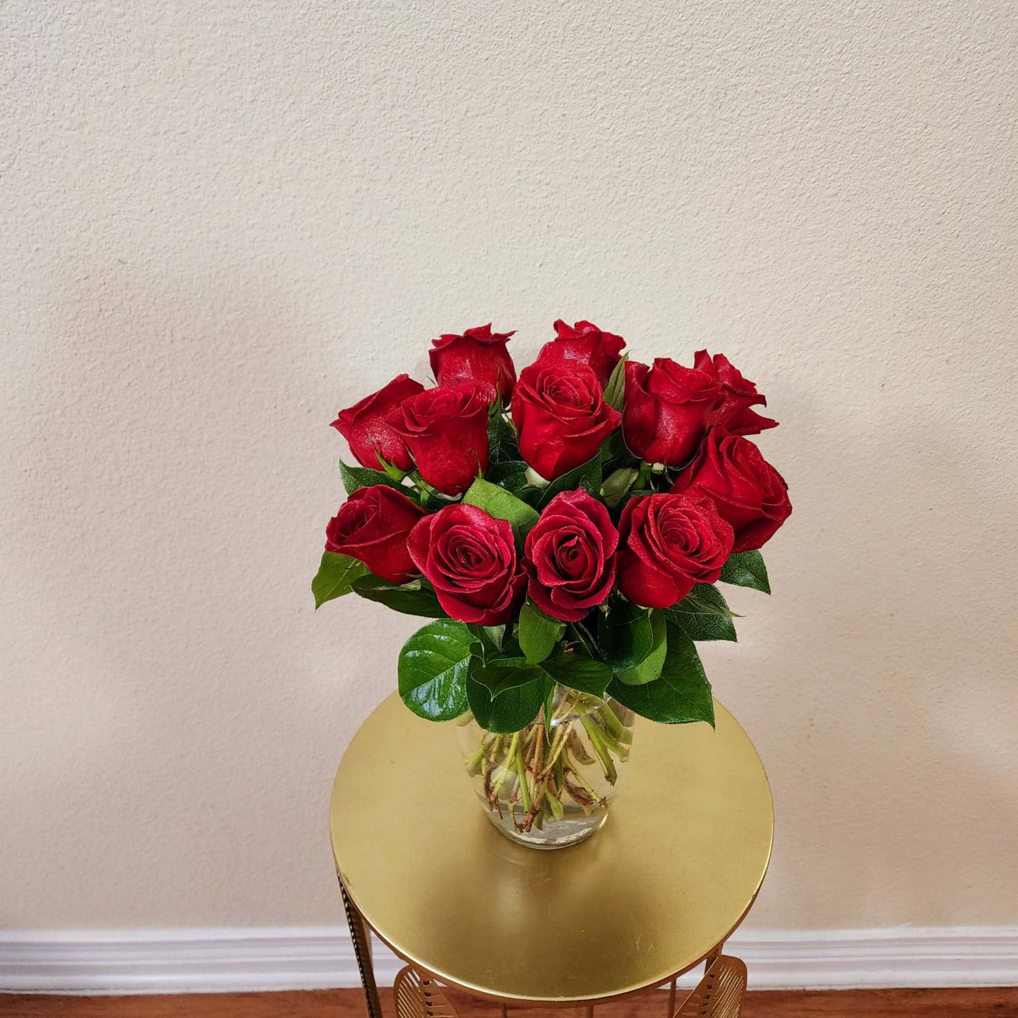 Roses in a clear vase with some greens in it, a classic