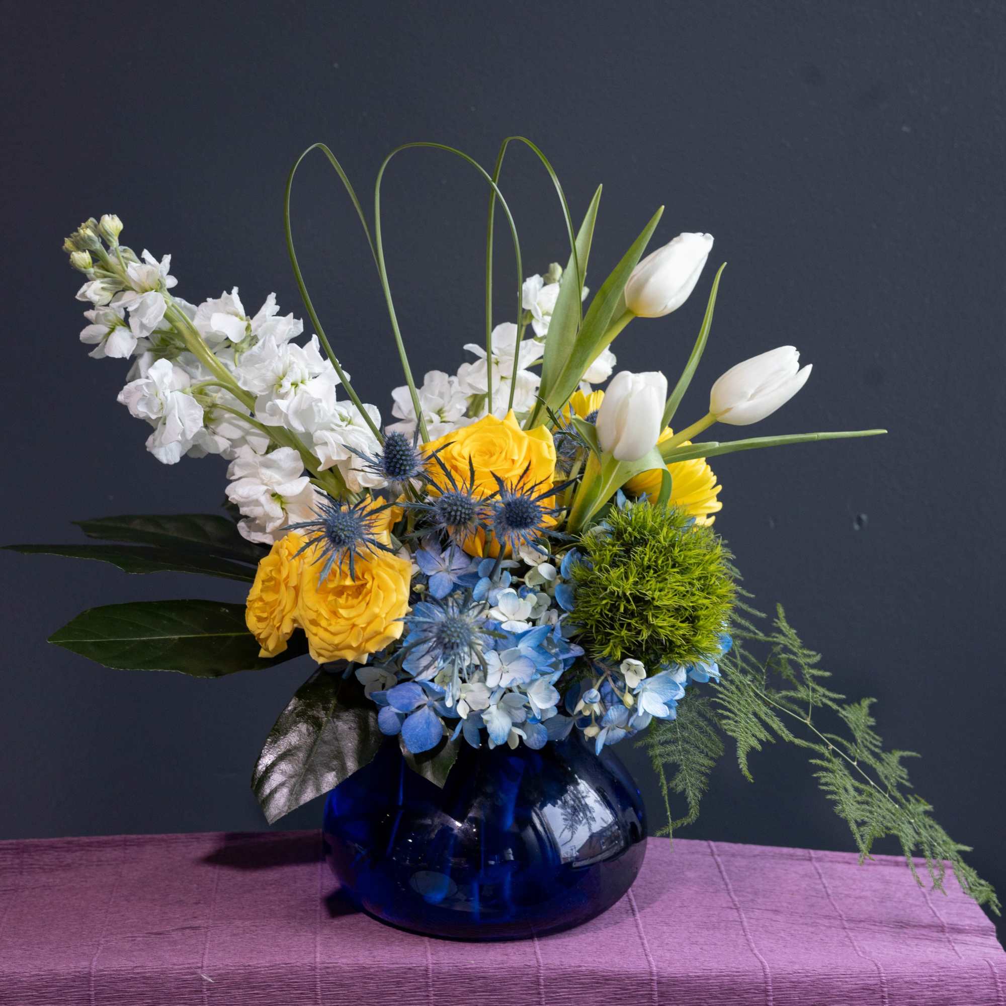 Together, the blue, white, and yellow flowers create a stunning visual spectacle