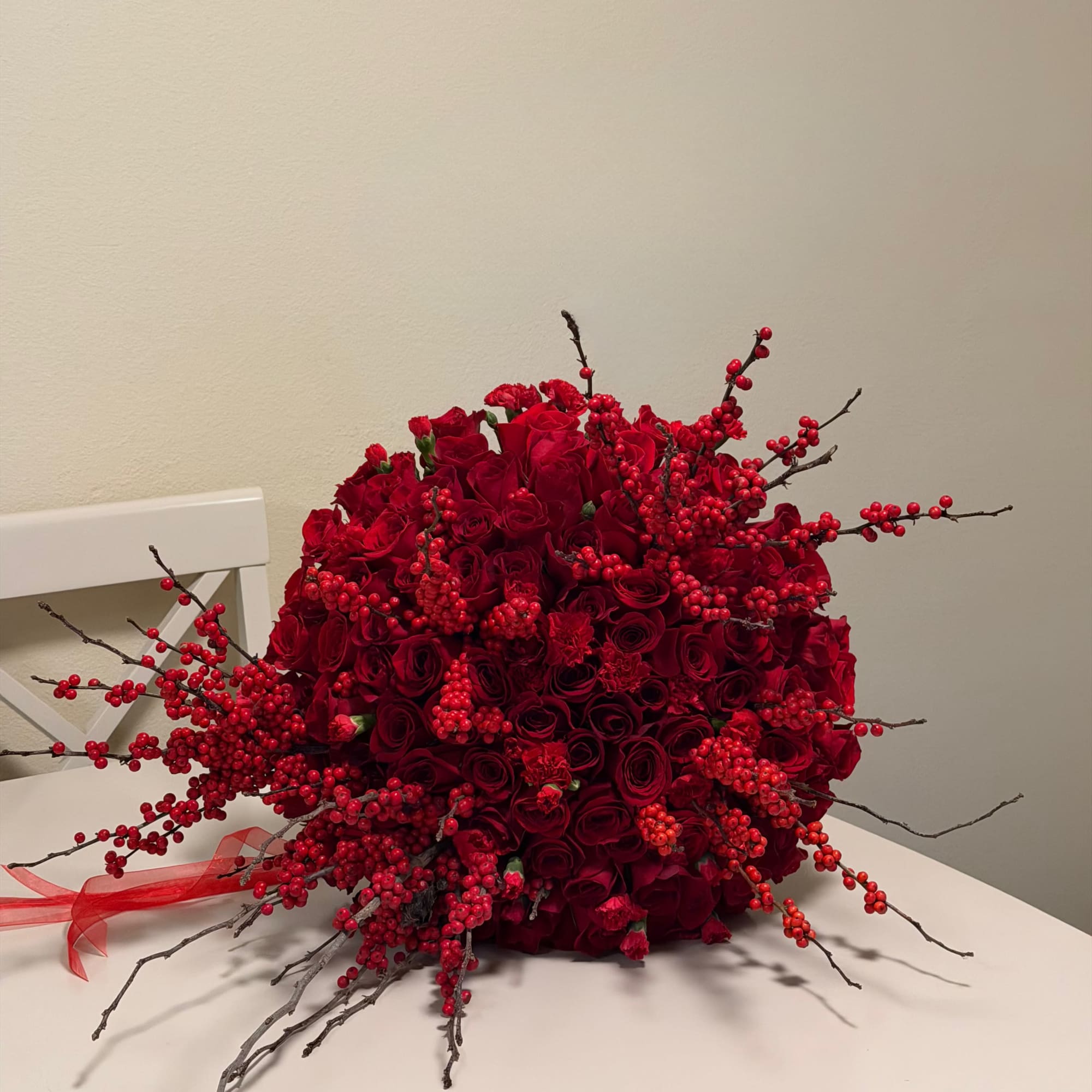 This striking arrangement features an abundant display of premium red roses, carnations