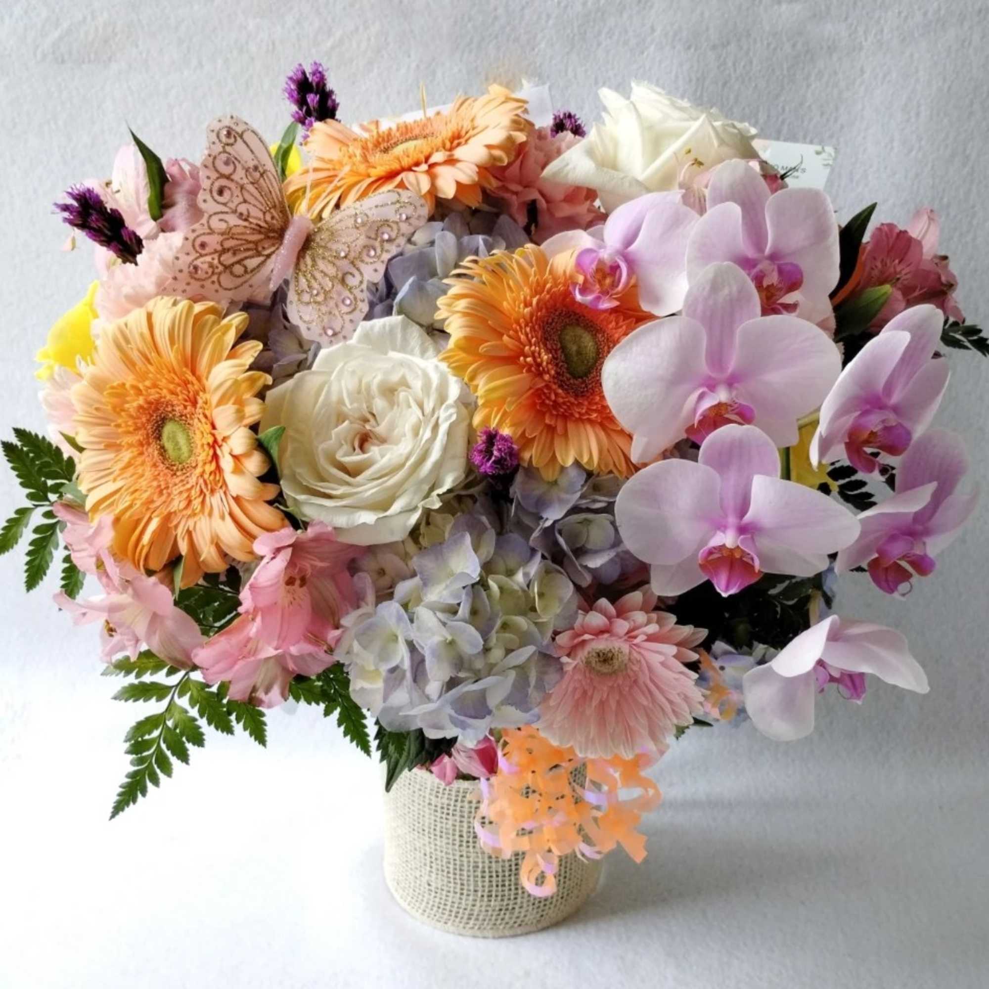 Lovely roses orchids and so much more arranged in a tall modern