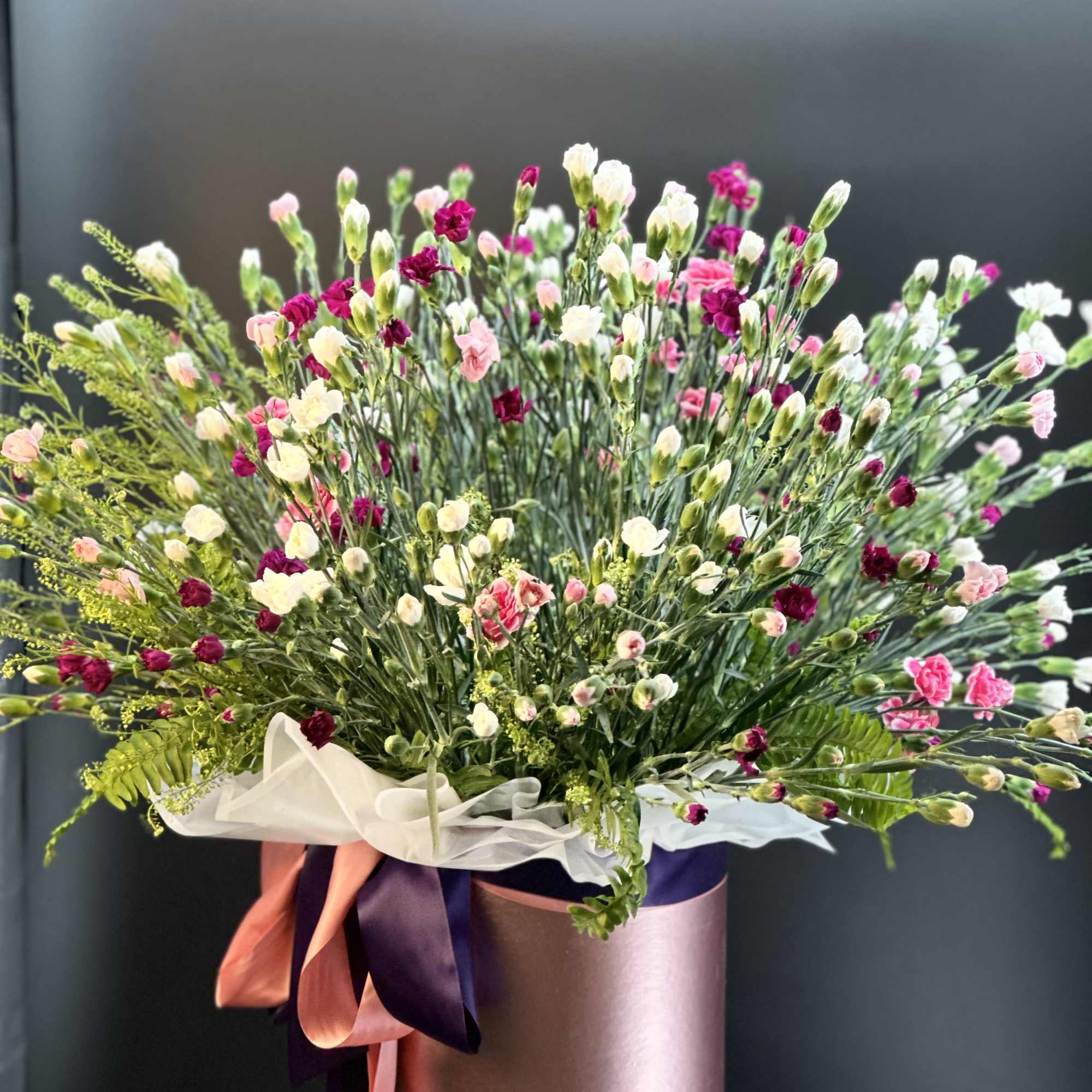 This arrangement is a full , mix carnation ,with greenery  garden