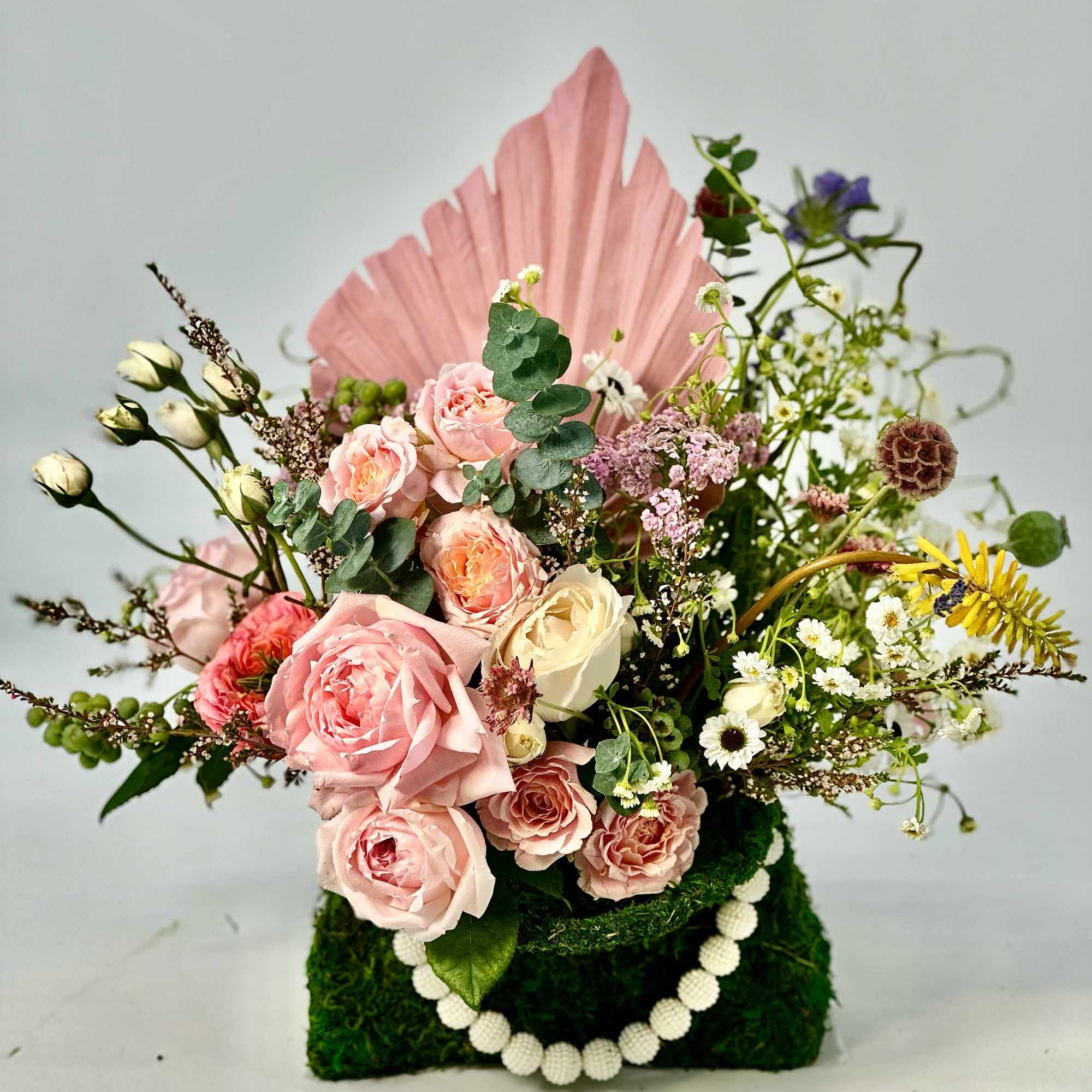 Refined ,low -profile floral arrangement composed of blush and rose -toned layered