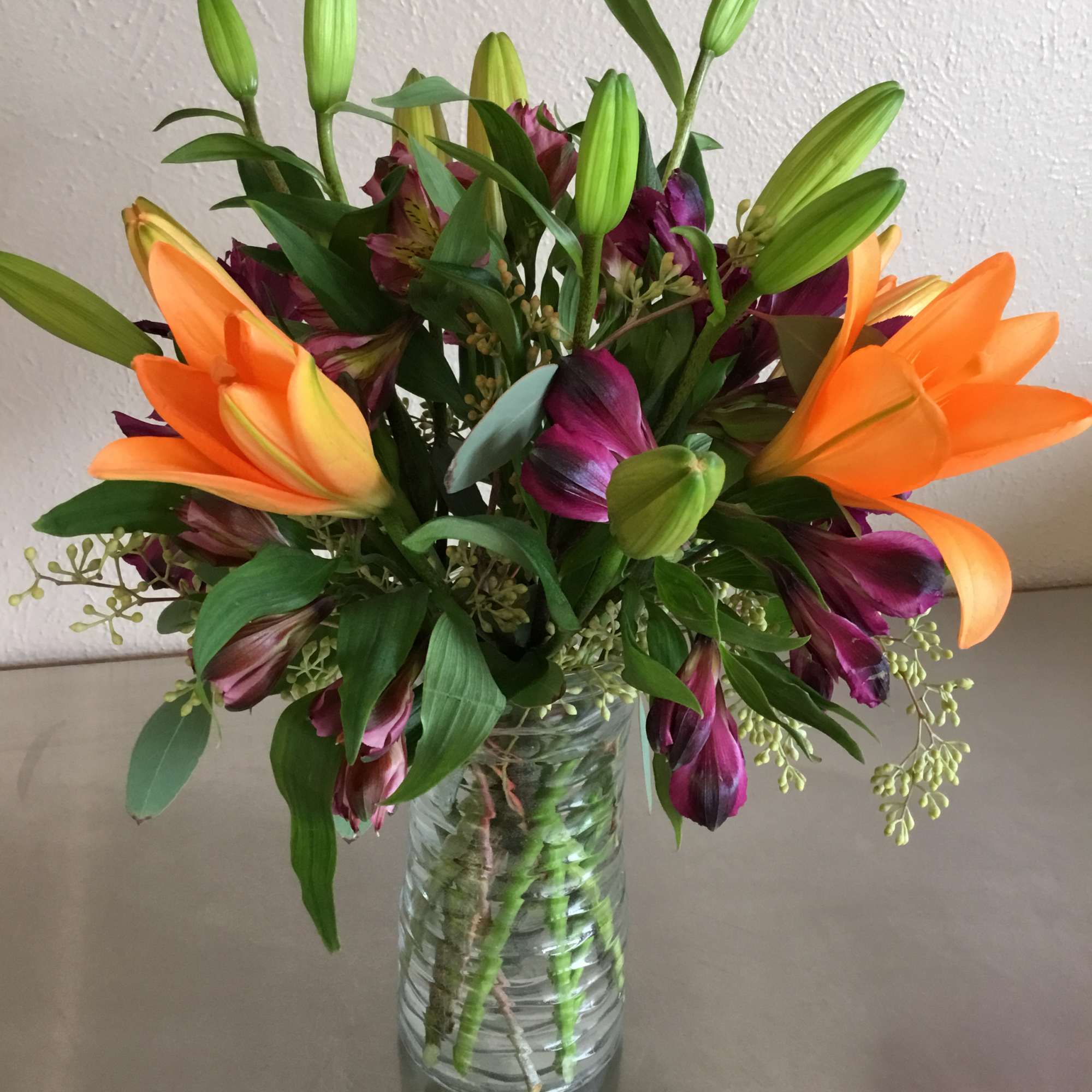 Brightly colored Asiatic lily (color may vary), complementary colored alstroemeria, and greenery