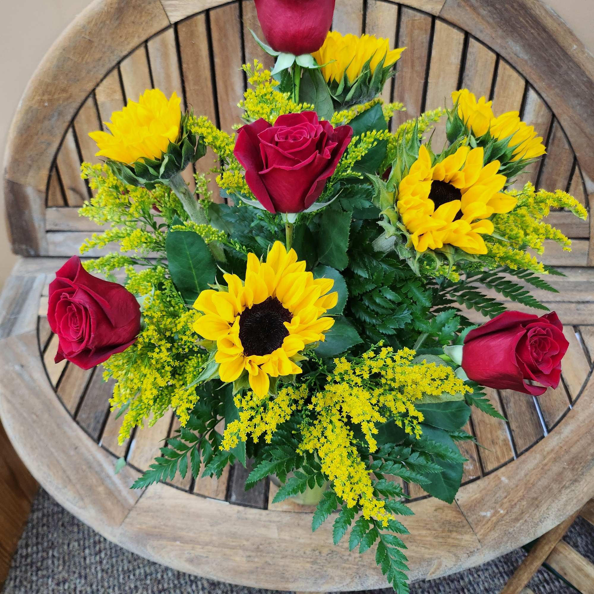 Sunflowers and Red Roses arranged in vase with greenery an filler.