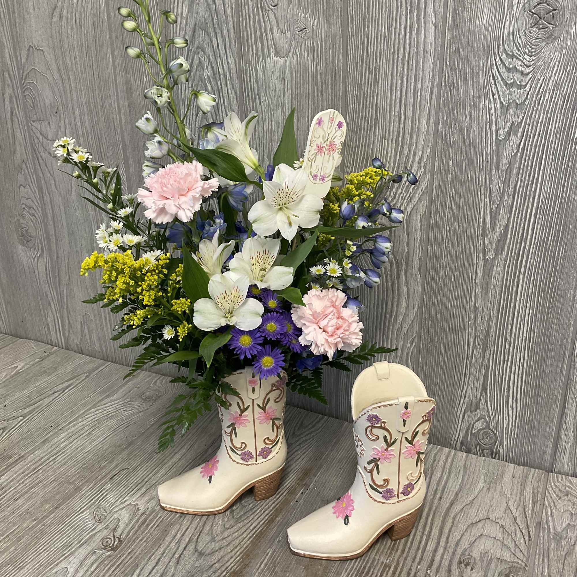 A southern wildflower arrangement in a resin boot vase. Flowers and colors
