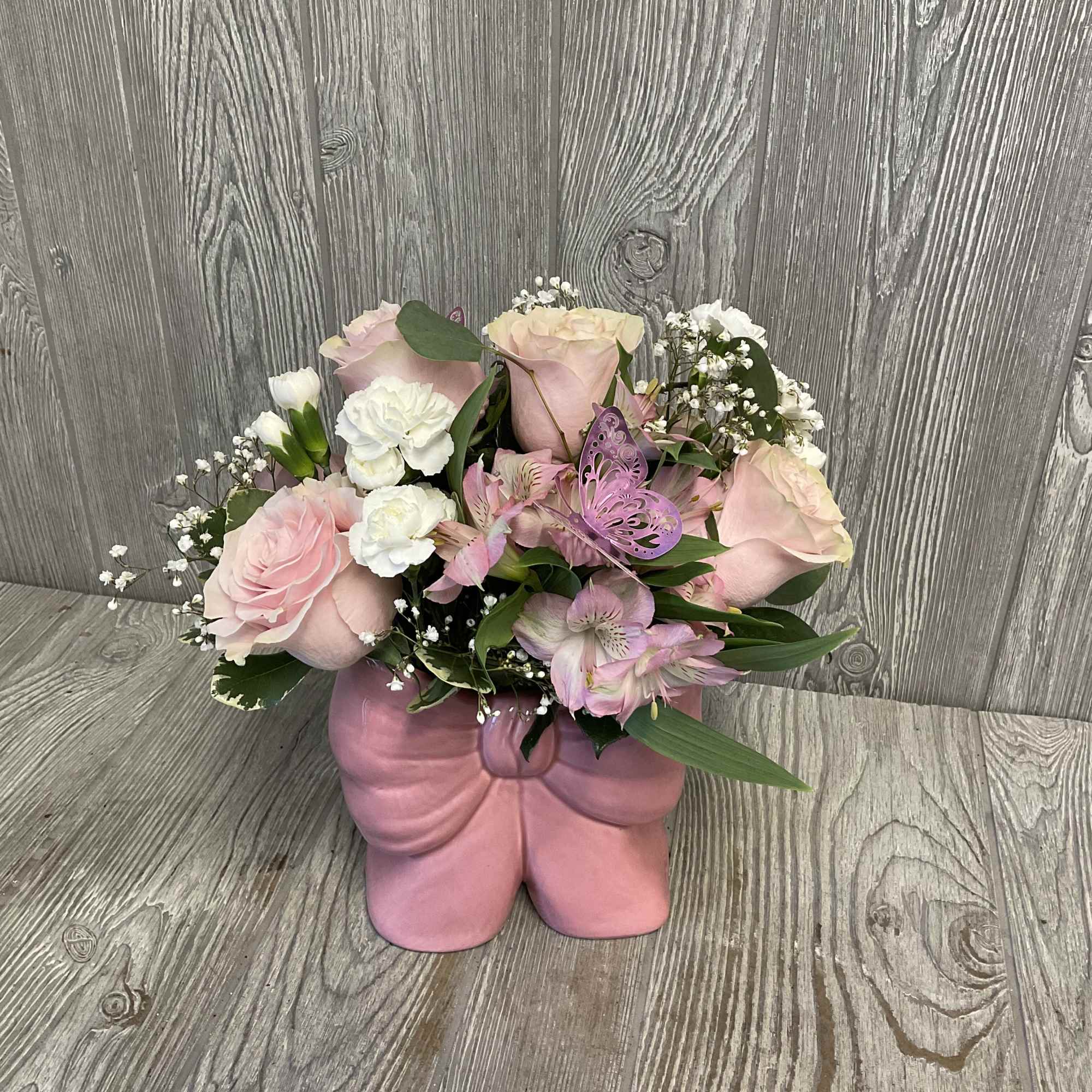 A lovely arrangement of fresh cut flowers arranged in a light pink