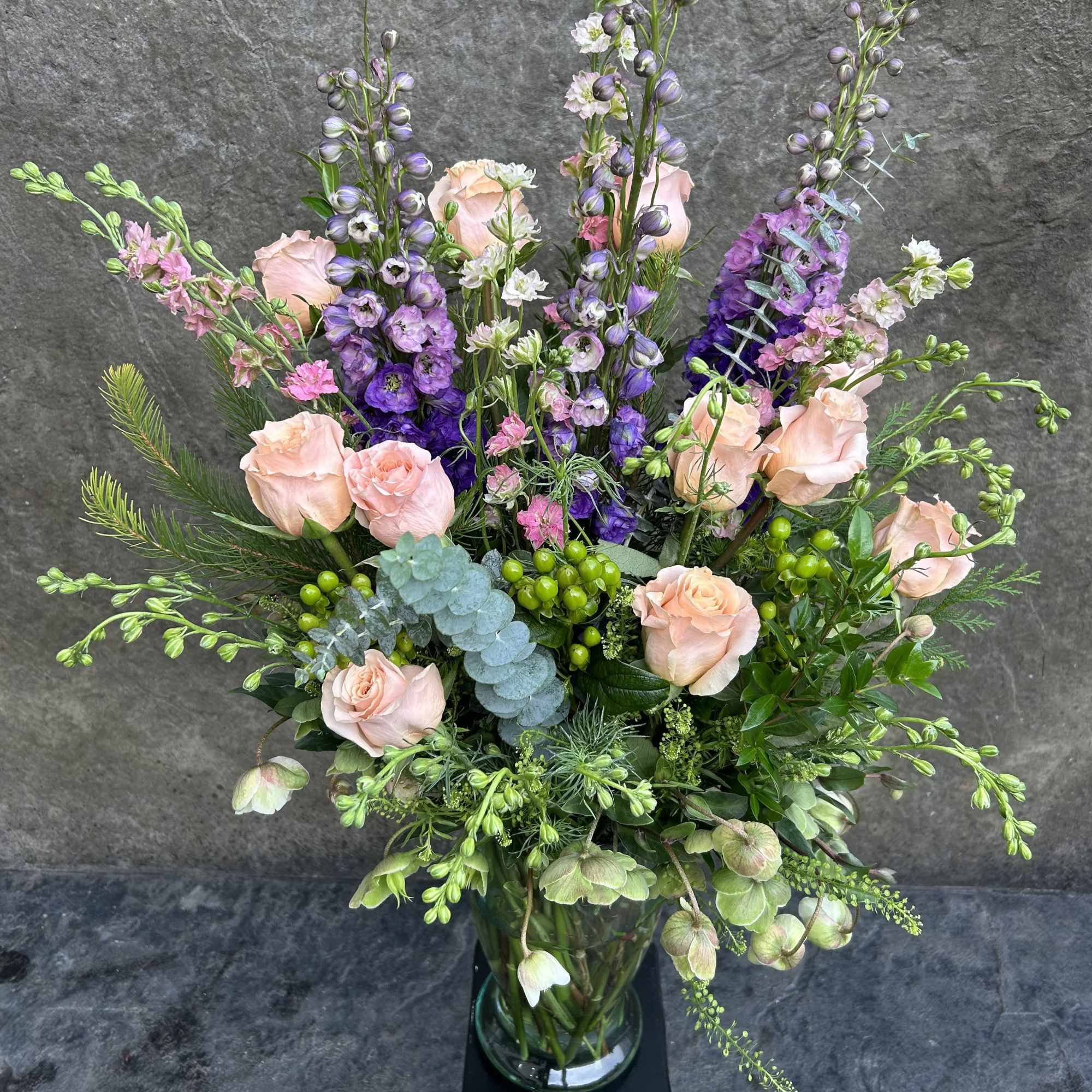 Peach roses, lavender delphinium, pink Larkspur, hellebore, berry, eucalyptus, and other pretty