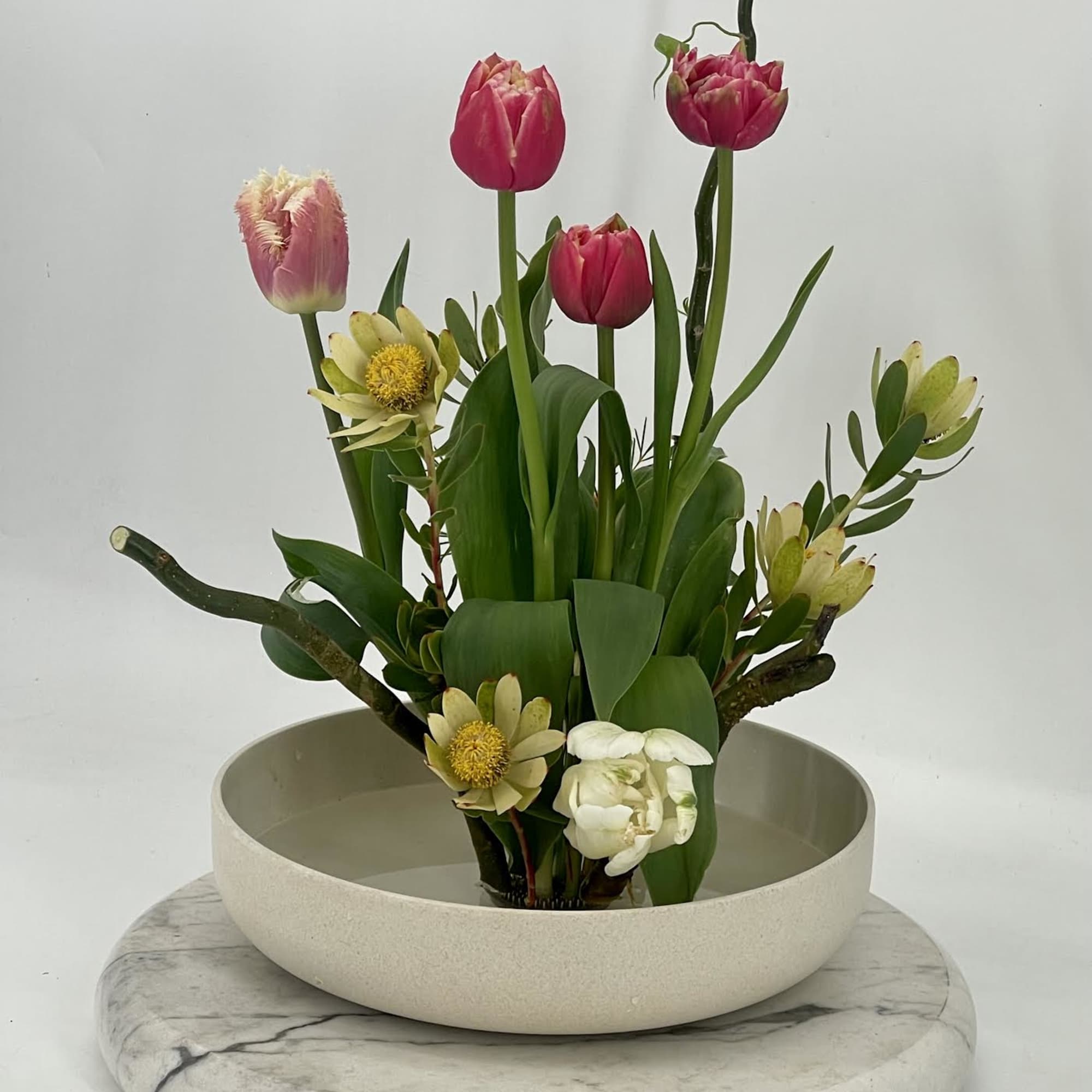 A refined Ikebana -style arrangement inspired by Japanese artistry .Sculptural blooms and