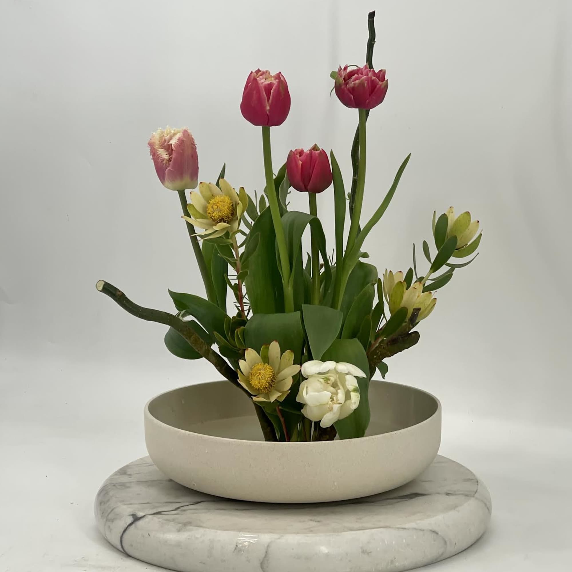 A refined Ikebana -style arrangement inspired by Japanese artistry .Sculptural blooms and