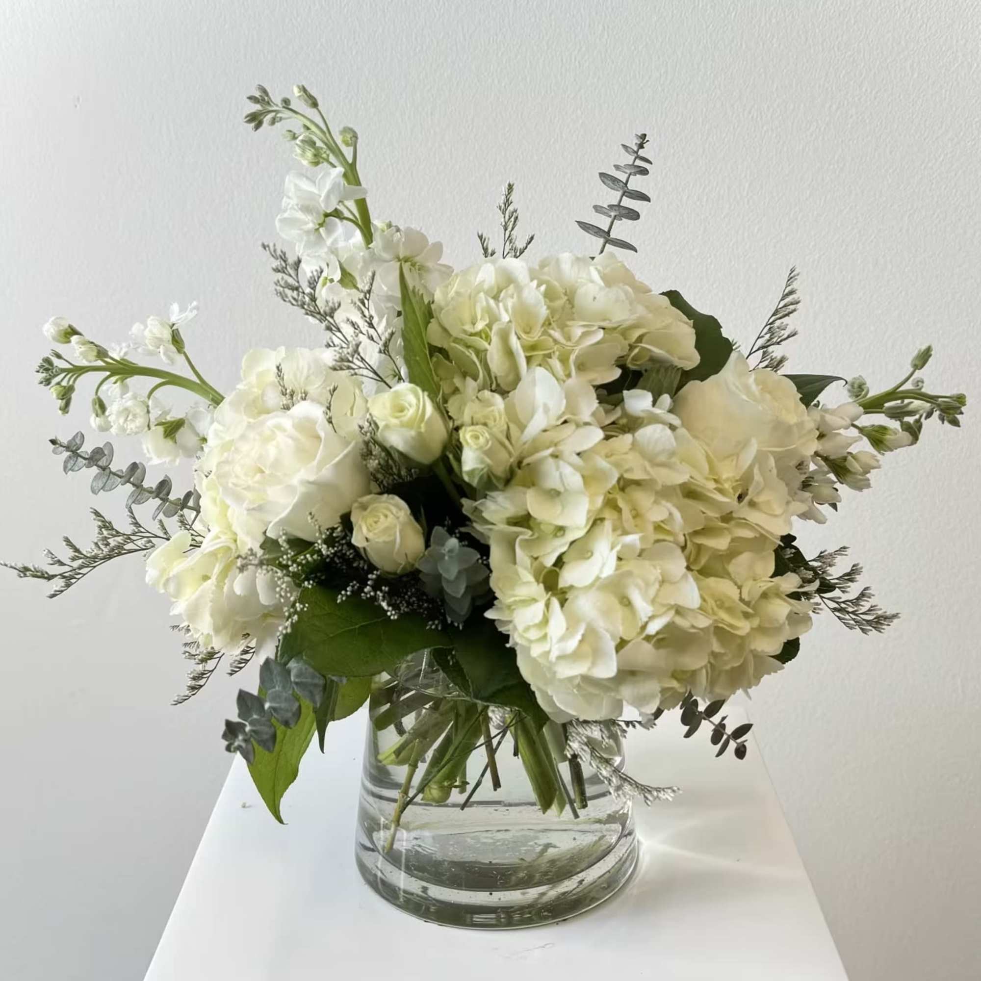 Discover the serene elegance of Simply Pure, an exquisite all-white flower arrangement