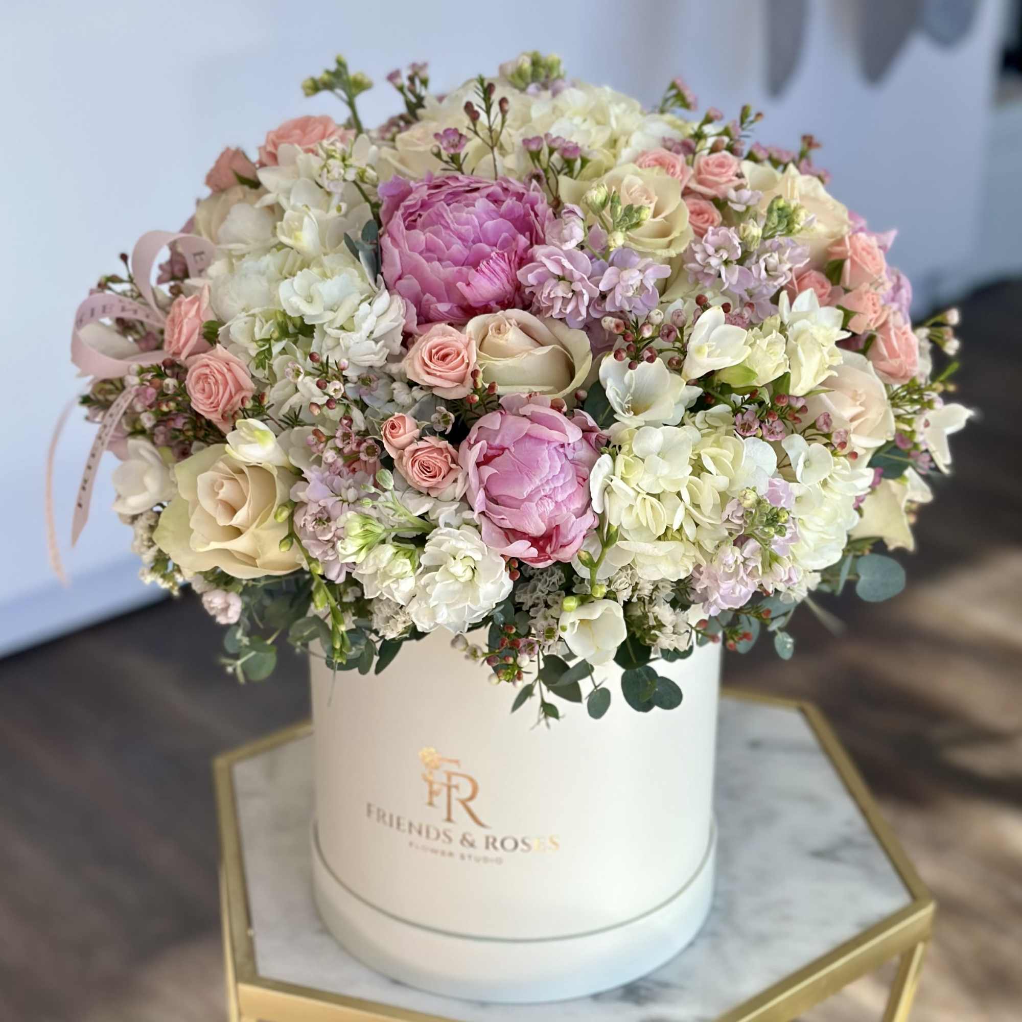 Elegant pastel flower arrangement featuring soft pink peonies, blush and ivory roses