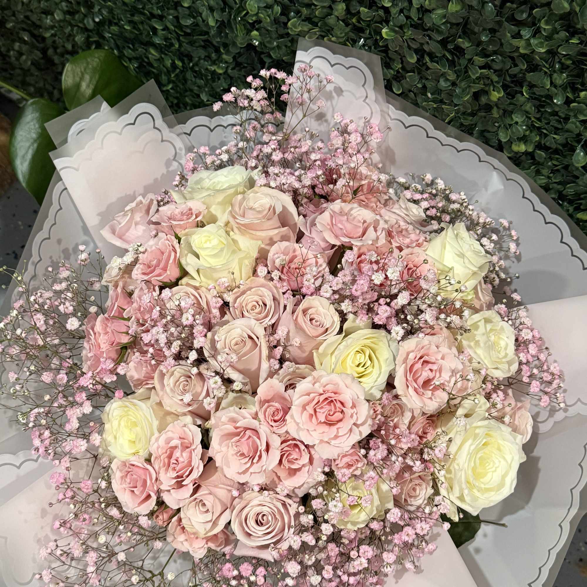 A dreamy wrapped bouquet featuring lush roses in pink, and creamy tones