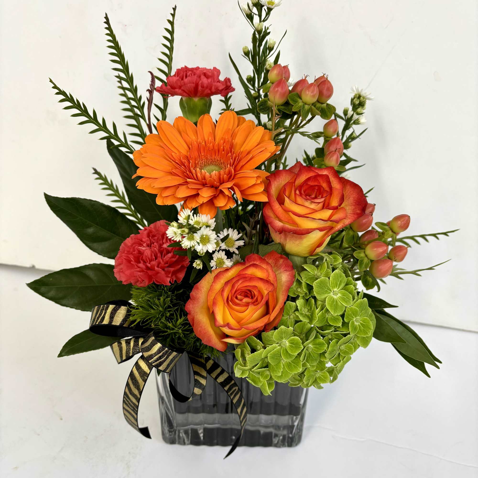 Ribbon tied cube vase with free spirit roses, hypericum, fatsia and hydrangeas