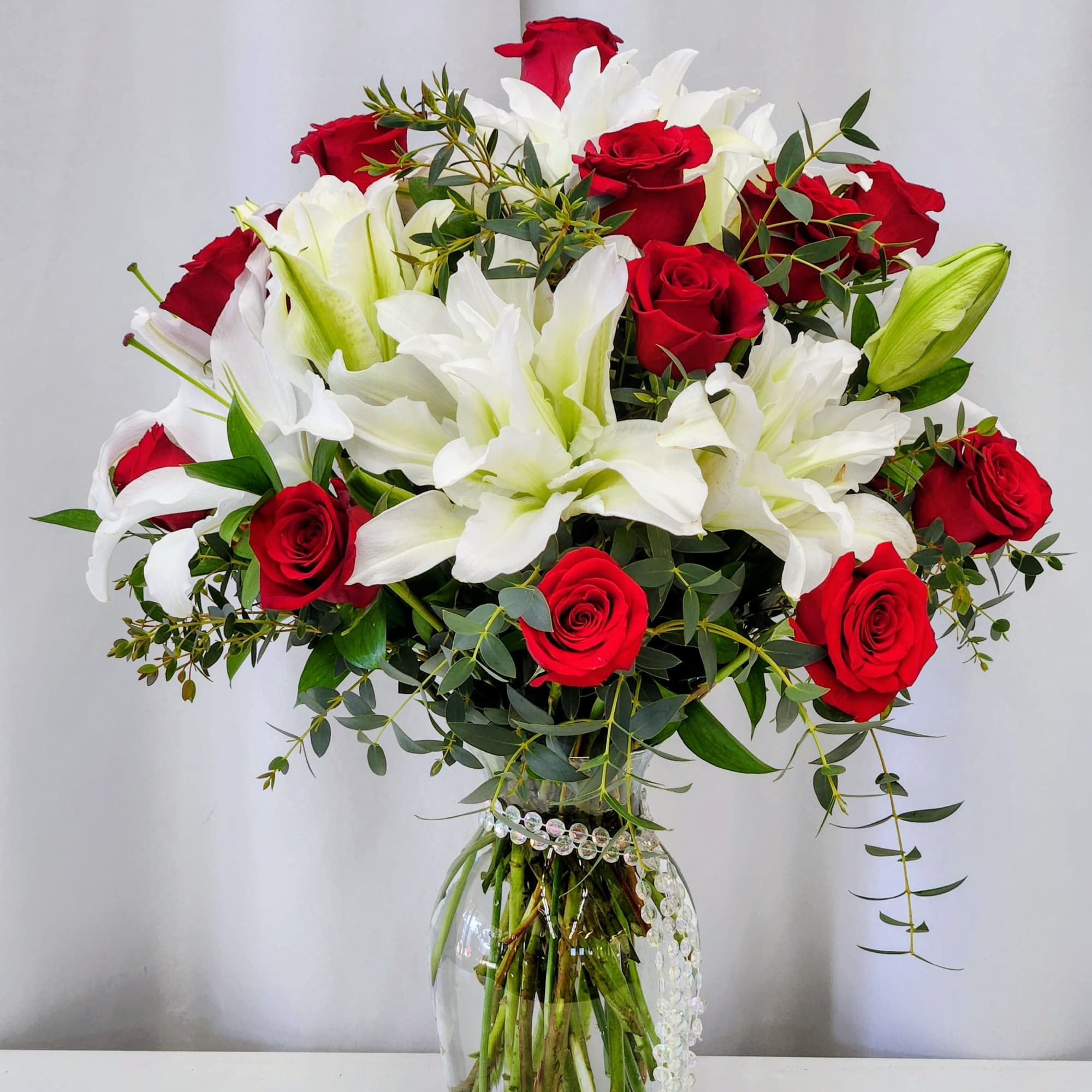 Red and white blooms unite in this dramatic arrangement, pairing velvety red